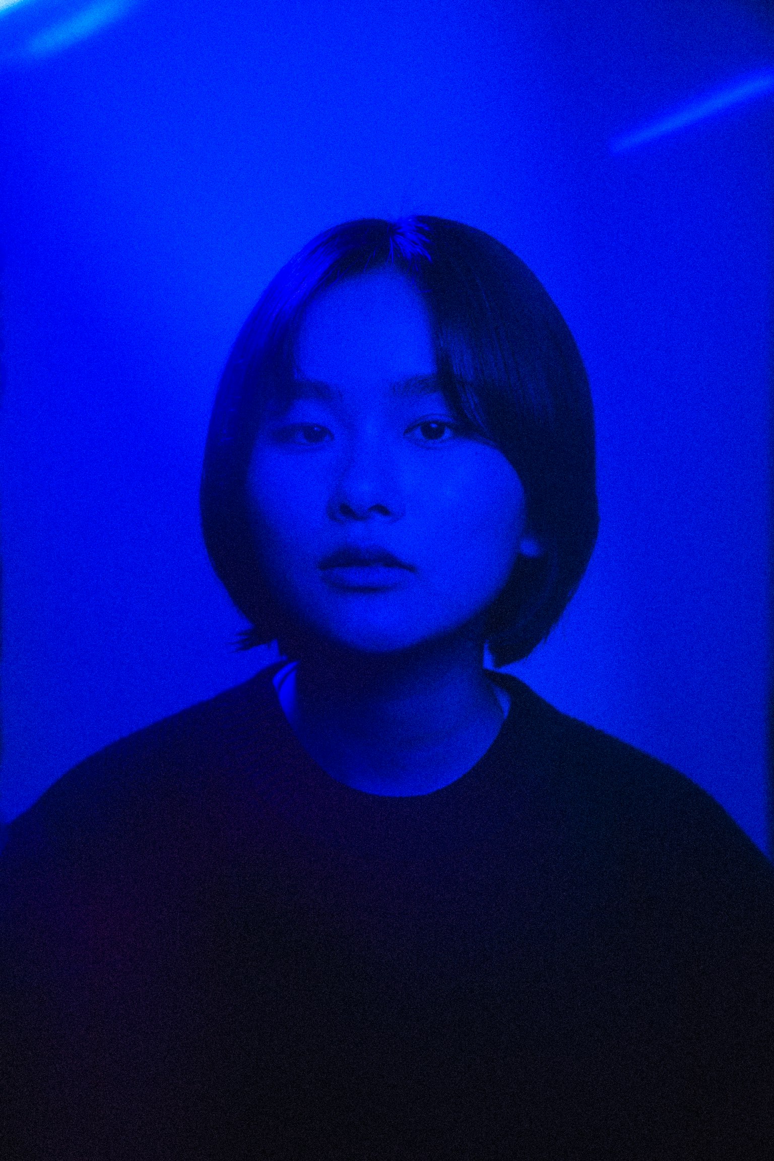 Ritratto di una persona con capelli corti illuminata da luce blu