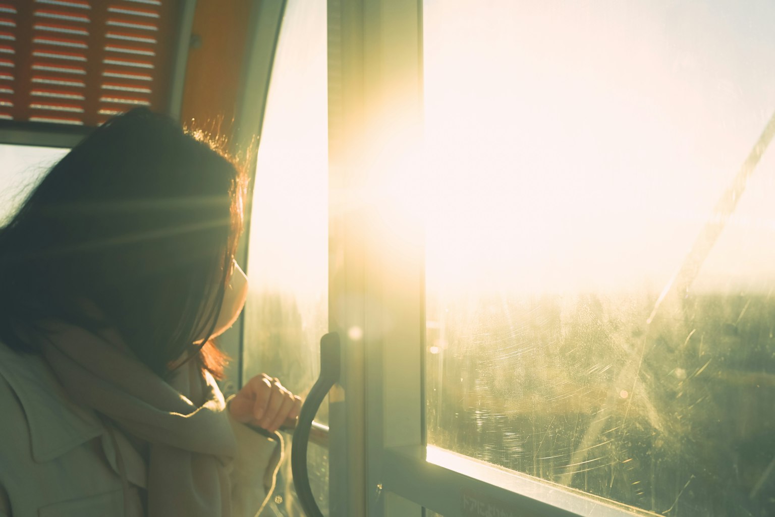 Femme regardant par la fenêtre avec la lumière du soleil qui entre