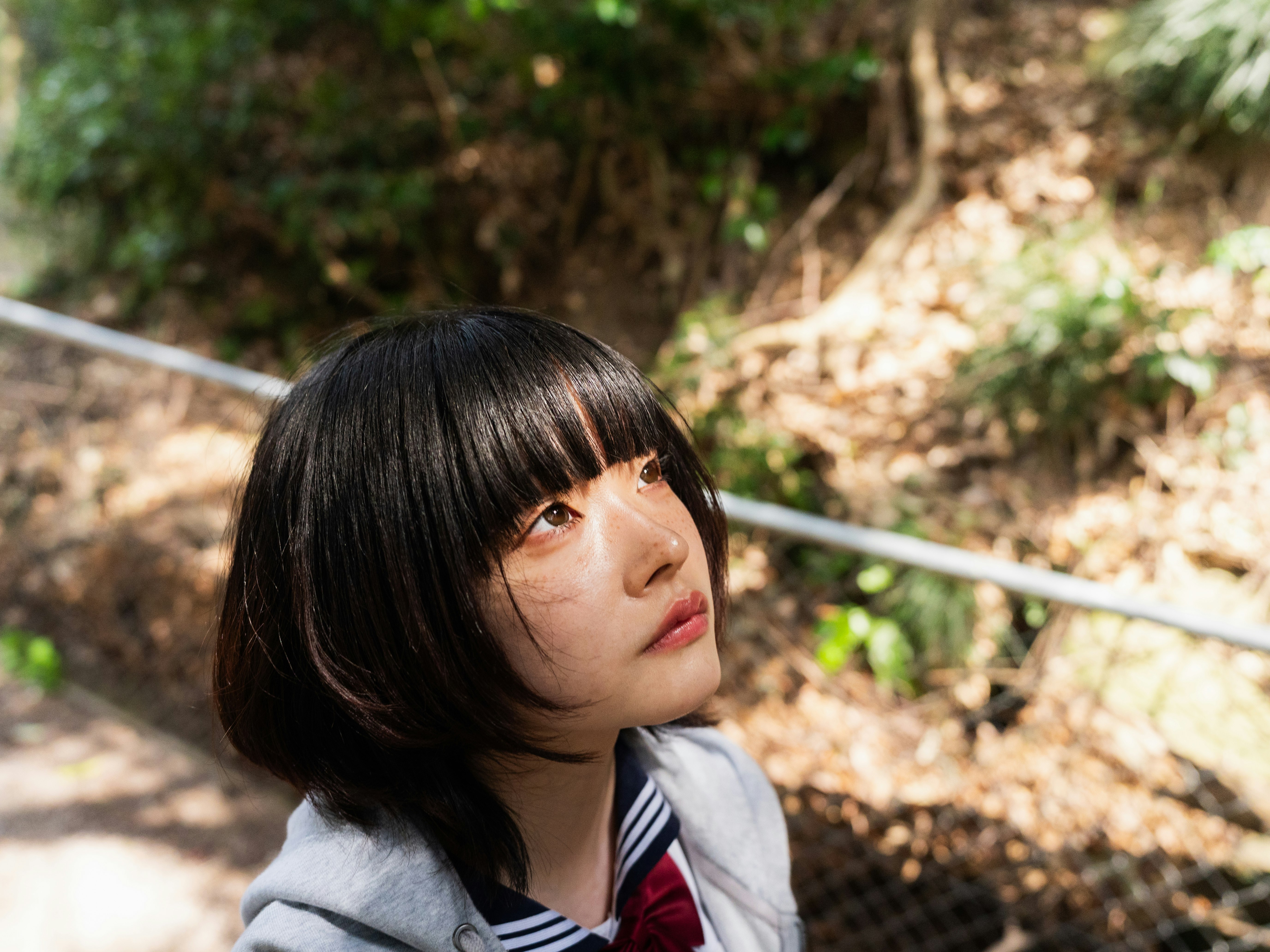 自然の中でフェンス越しに見つめる女性