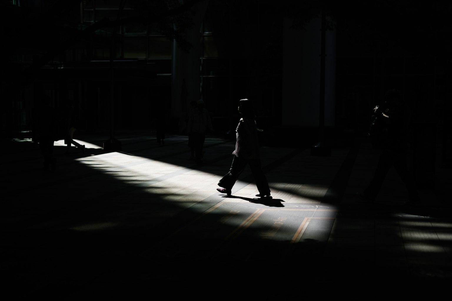 Una persona che cammina in un raggio di luce su uno sfondo scuro