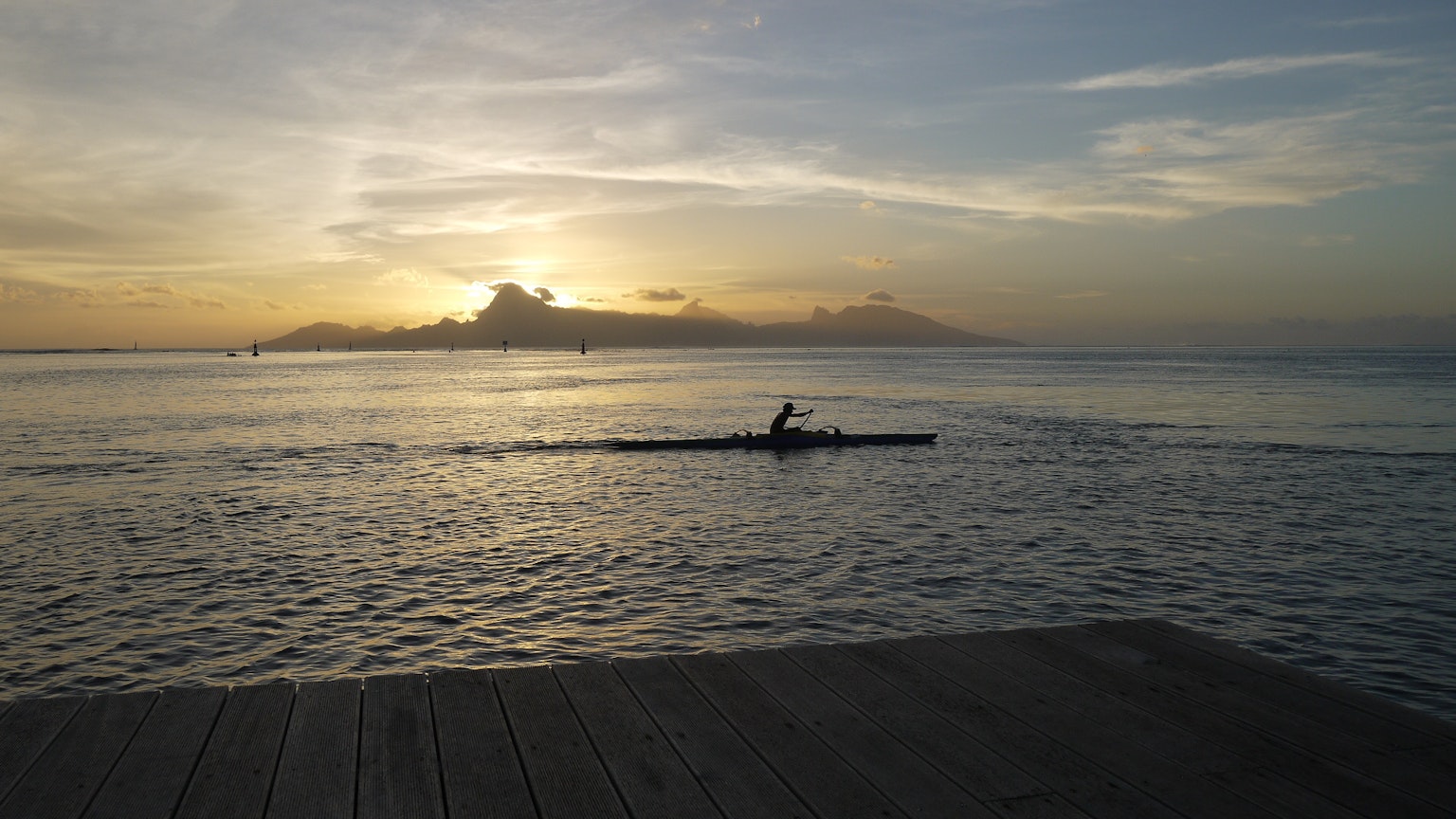 Una persona remando en kayak contra un fondo de atardecer con aguas tranquilas