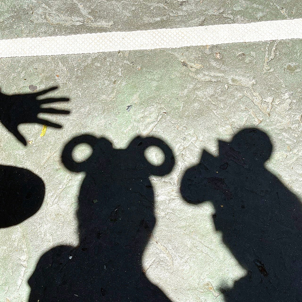 Hand and human shadow silhouettes on pavement