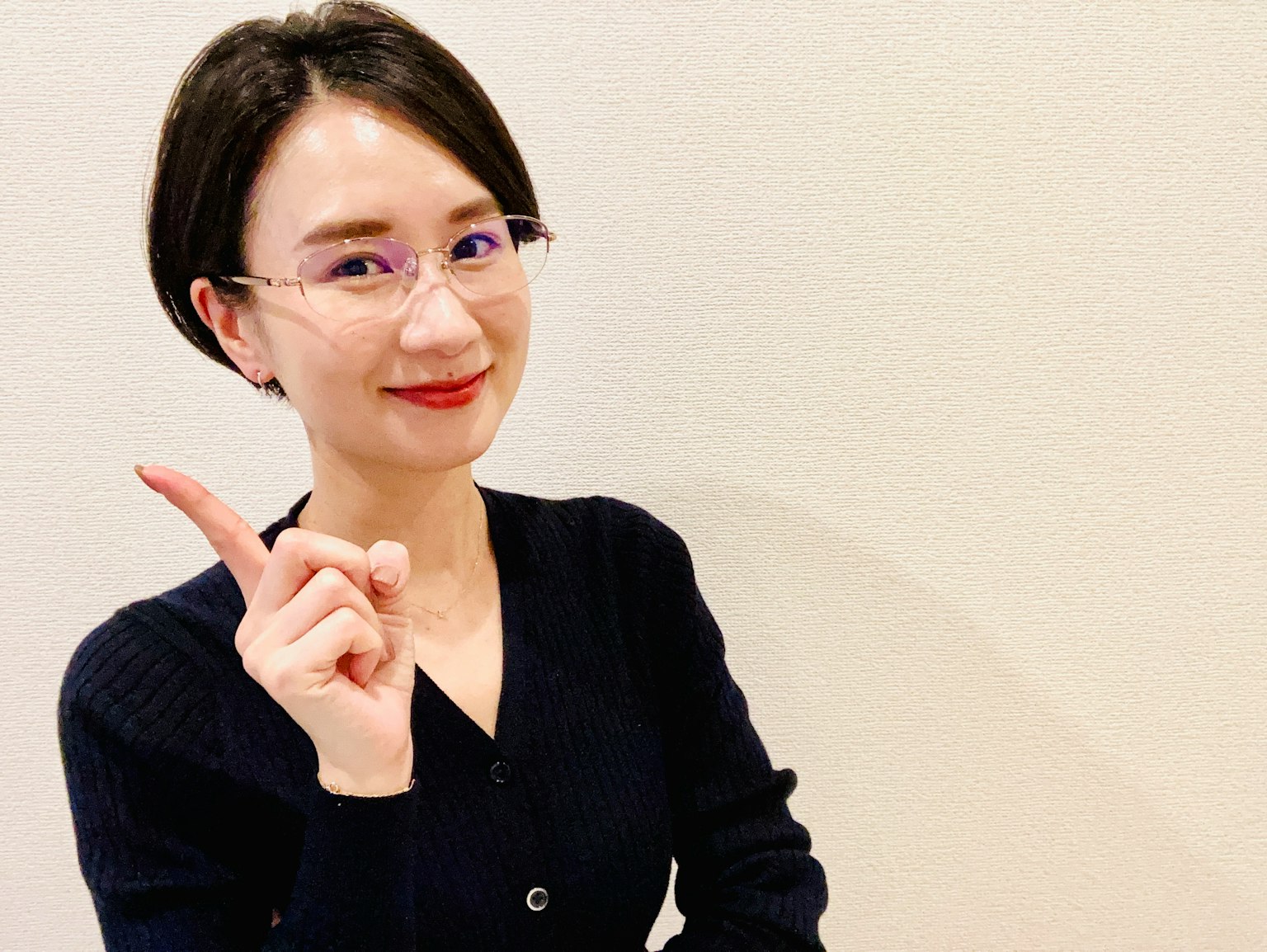 穿著黑色毛衣的女性微笑著指著