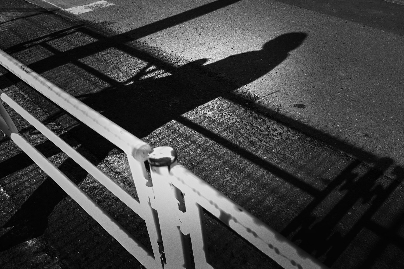 Silhouette d'une personne marchant devant une clôture en noir et blanc