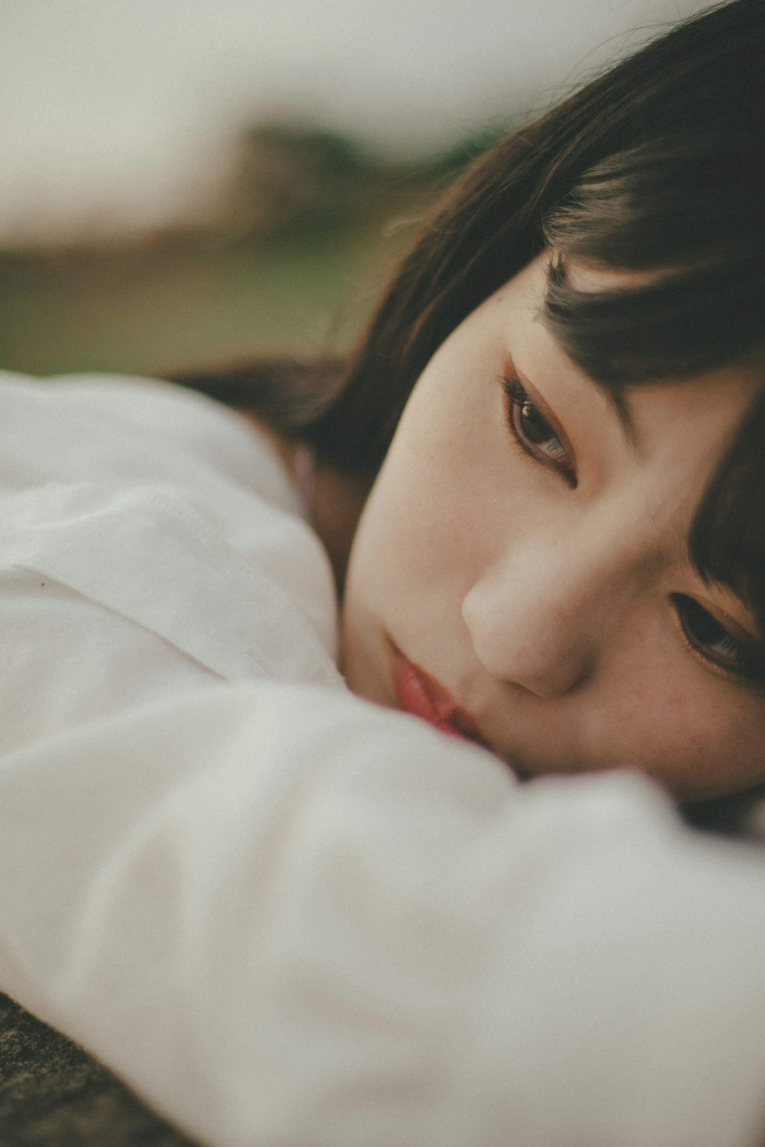 女性靠在手臂上的特写镜头，神情沉思，背景柔和