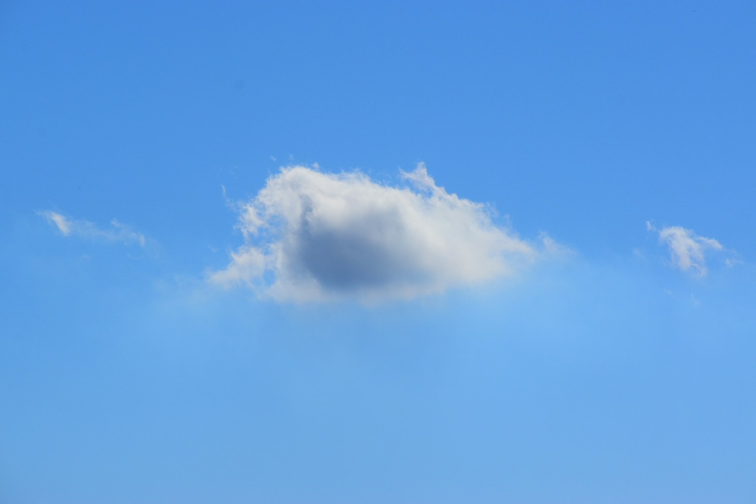 Eine einfache Landschaft mit einer weißen Wolke, die in einem blauen Himmel schwebt