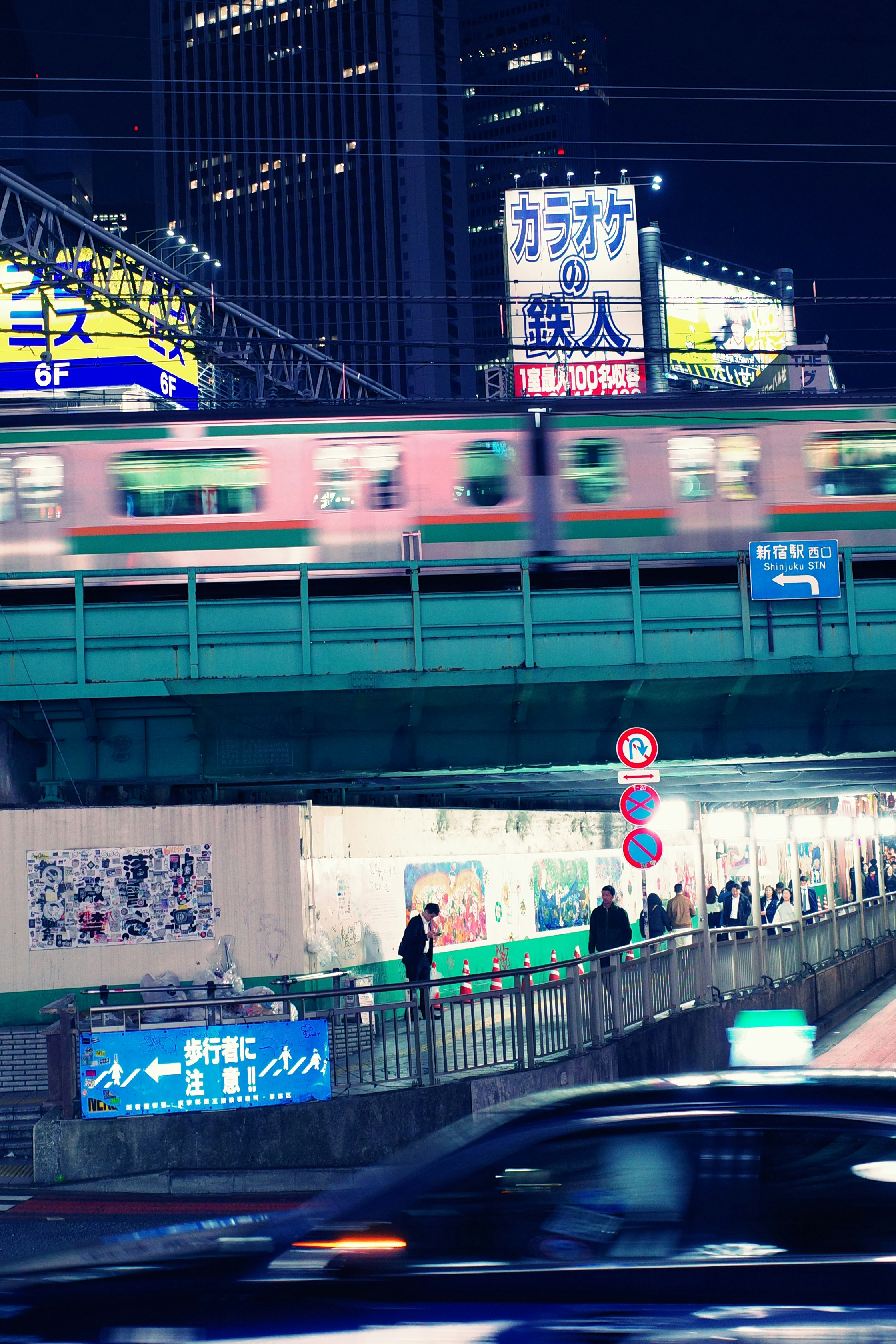 夜の高架駅と行き交う電車・車のある街の風景