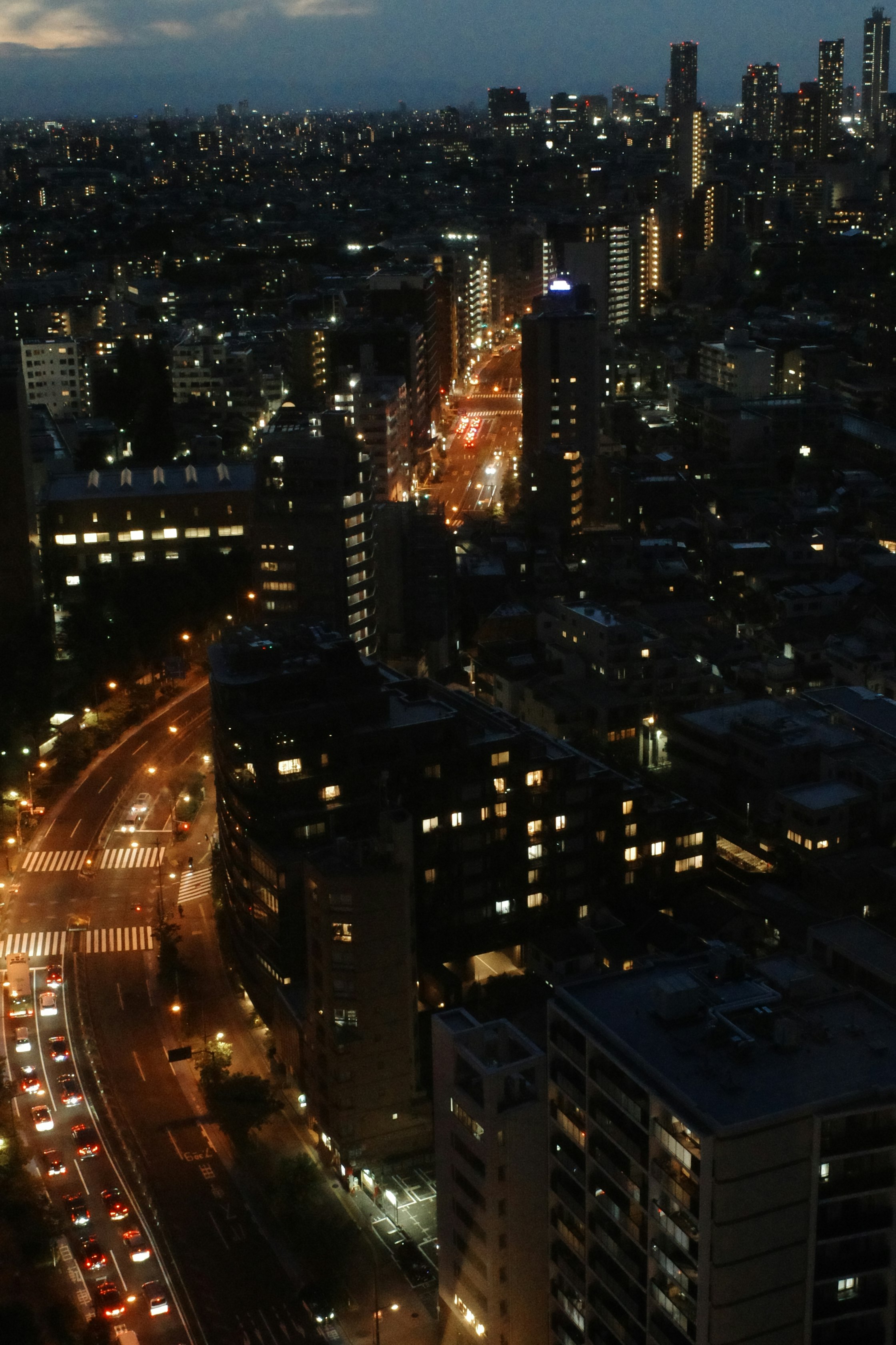 夜の高層ビル街を走る車の光が続く大通り