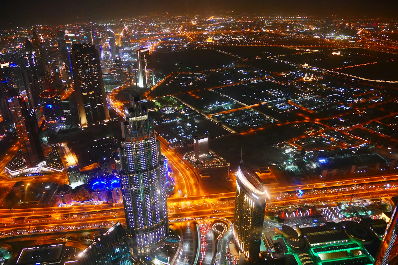 Aerial view of Dubai's skyline at night with illuminated buildings and roads