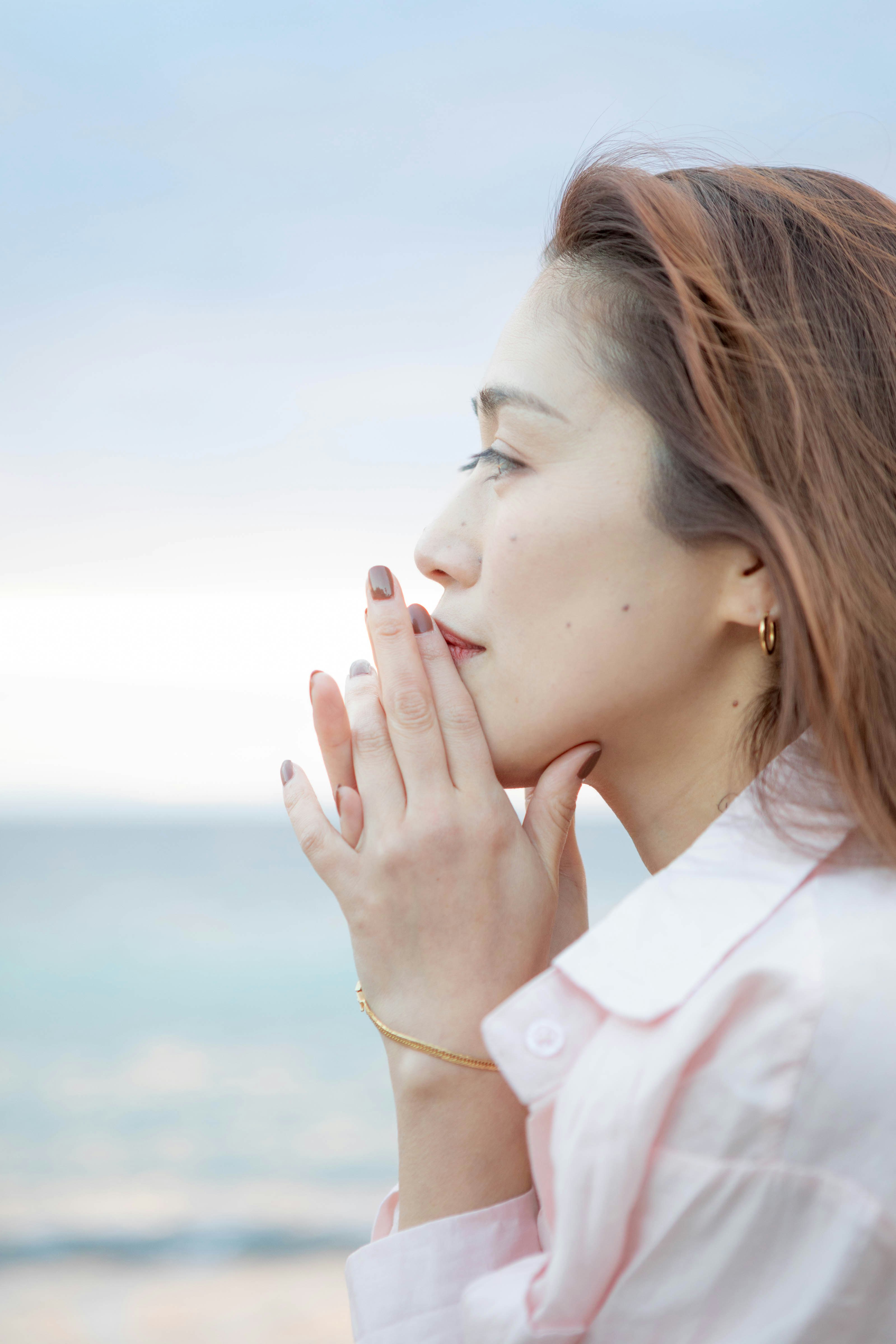 海辺で頬に手を添える女性