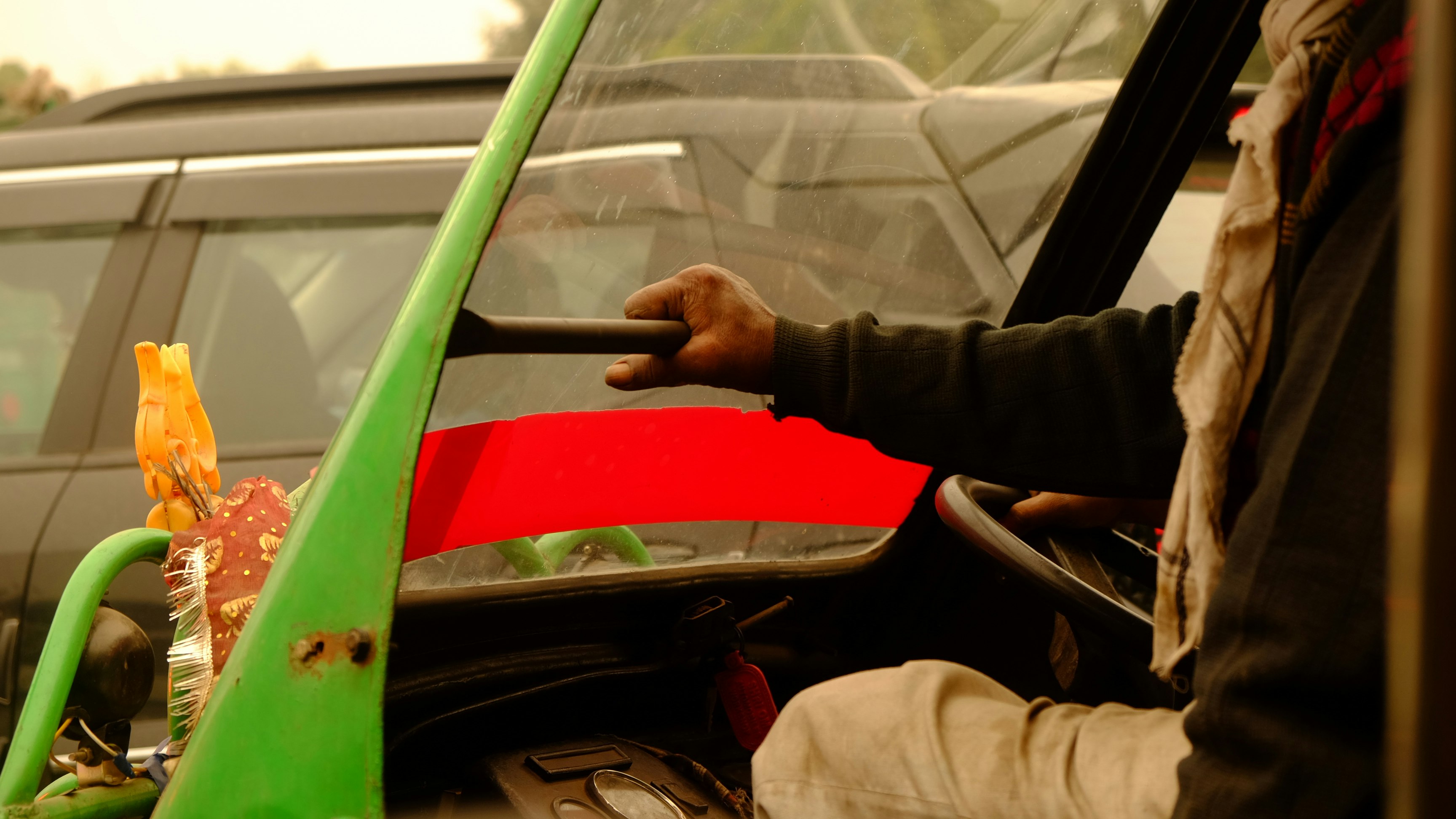 車の窓から手を差し出す人と緑のホースのある作業風景