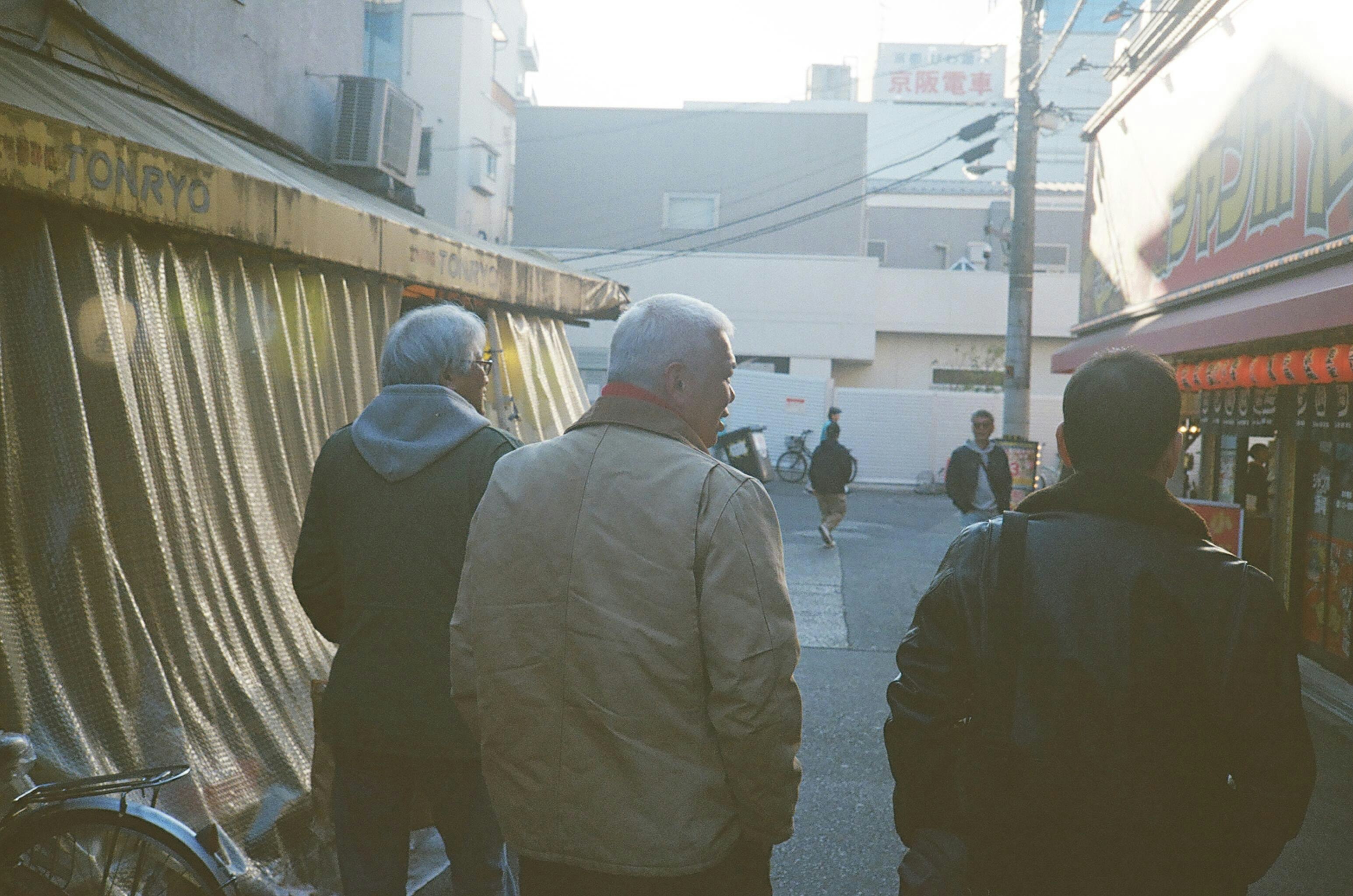 路地の奥を見つめる友人たちの後ろ姿