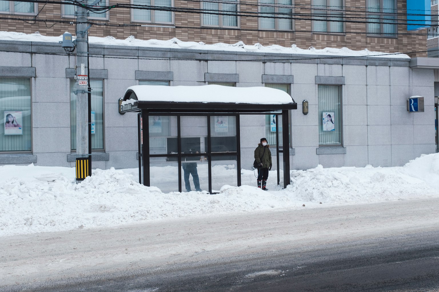Person waiting at a snow-covered bus stop