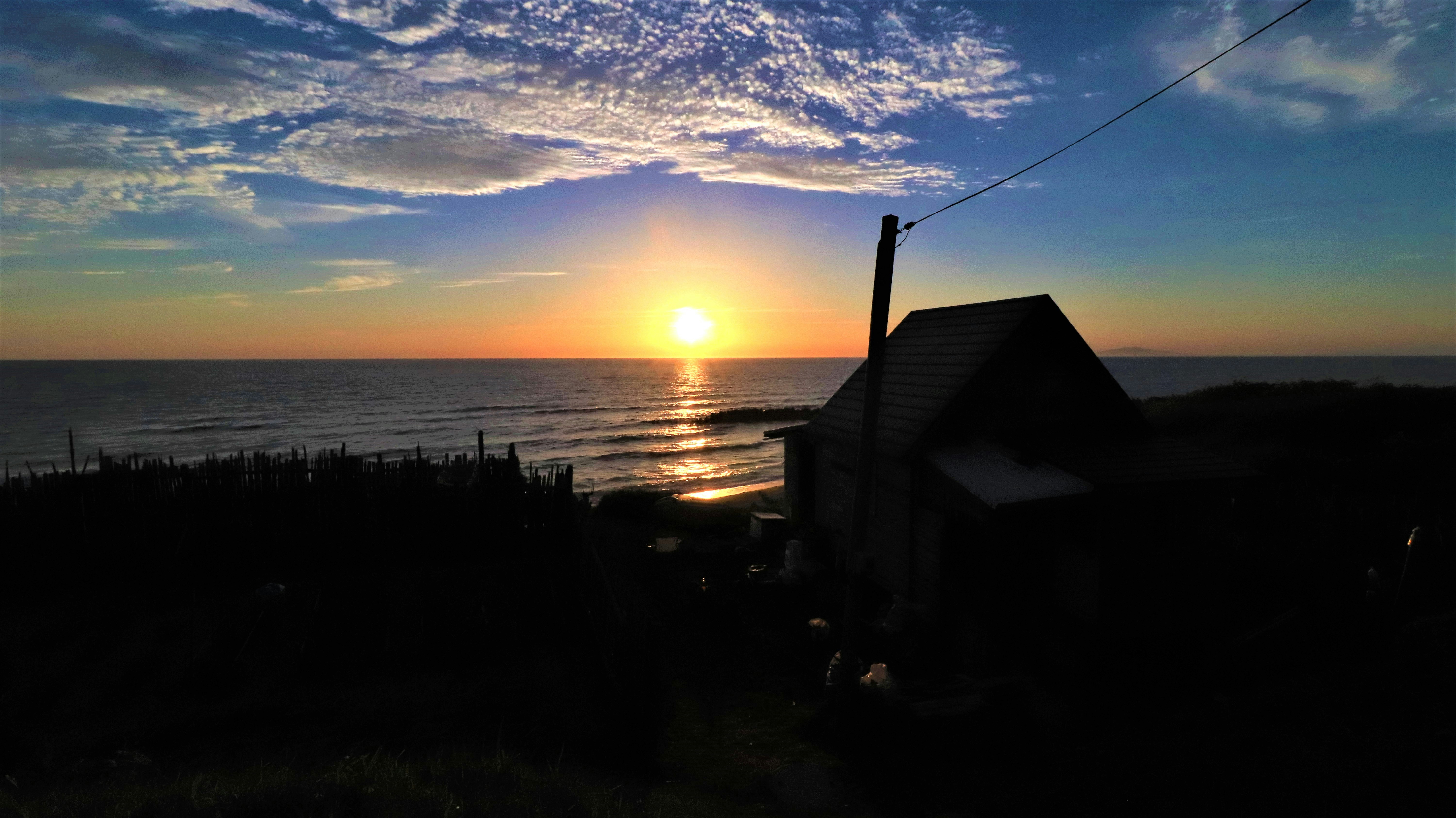 夕日に照らされた海辺の家と波のある風景