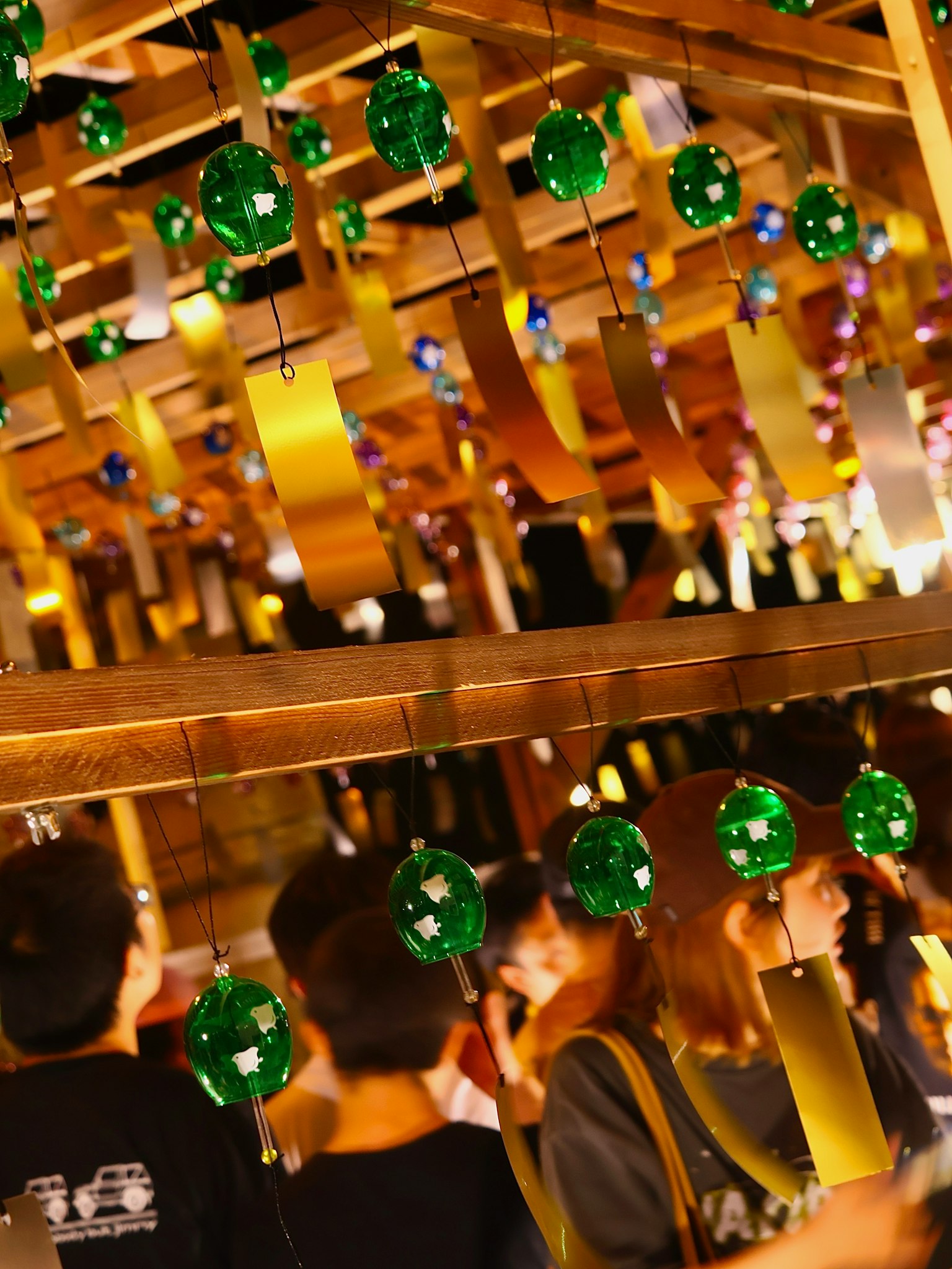 Festival scene with green wind chimes and golden strips hanging people gathered