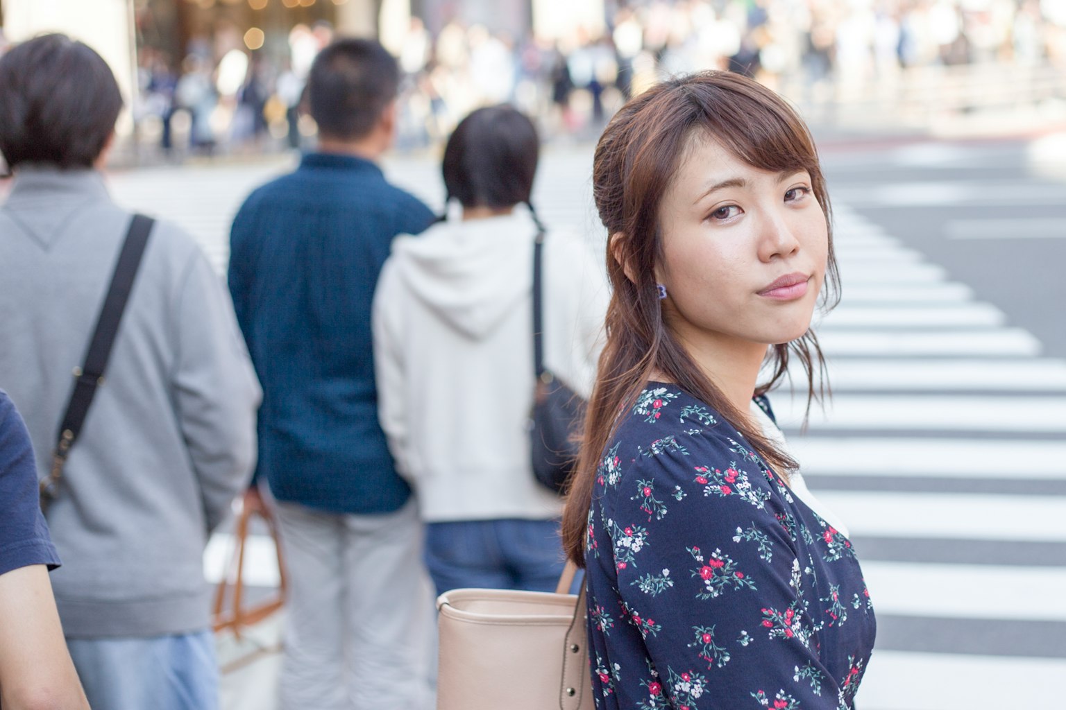 ผู้หญิงรอที่ทางม้าลายพร้อมผู้คนในพื้นหลัง