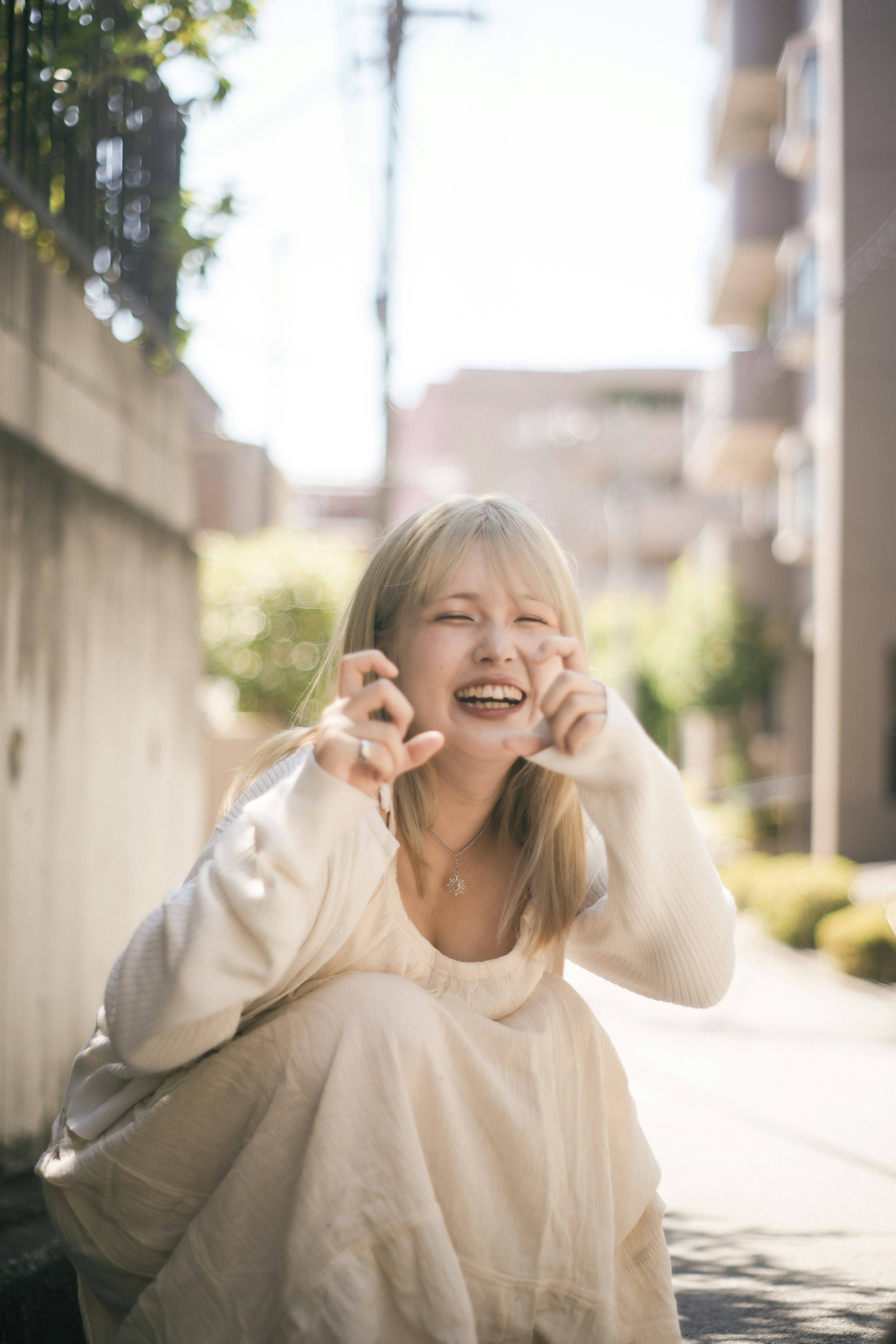 Một người phụ nữ trong chiếc đầm trắng tạo dáng cười dưới ánh nắng rực rỡ