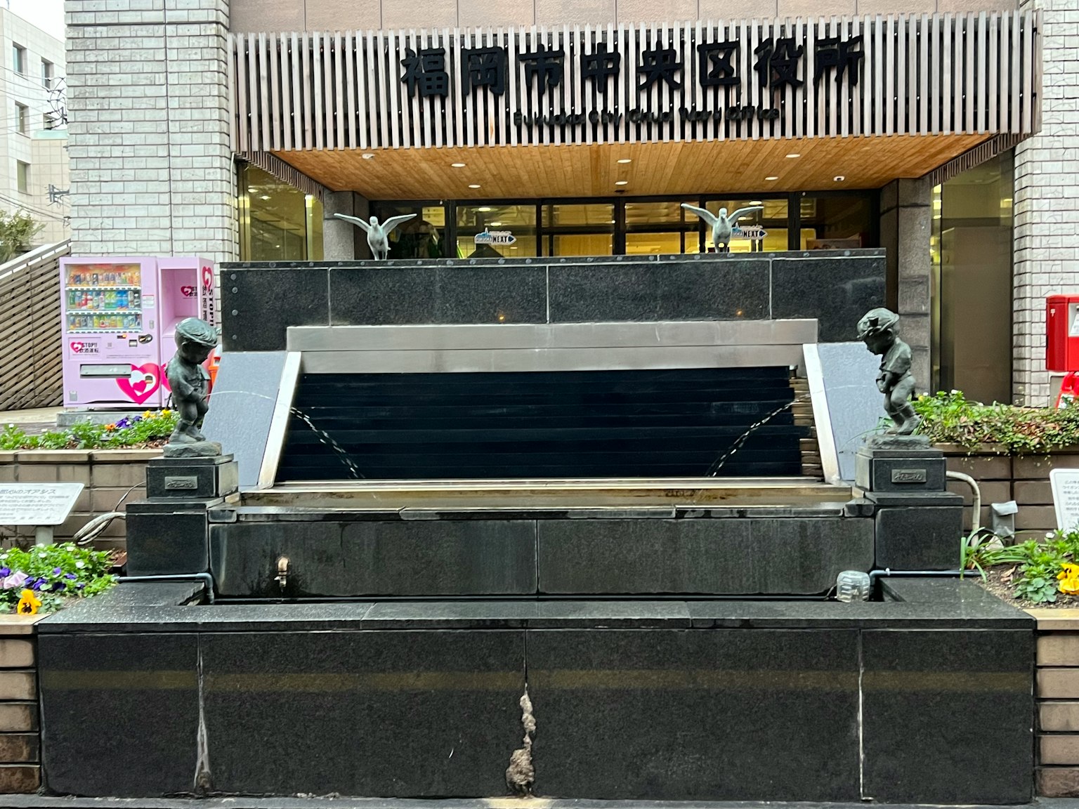 建築前的黑色石頭噴泉和兩座雕像