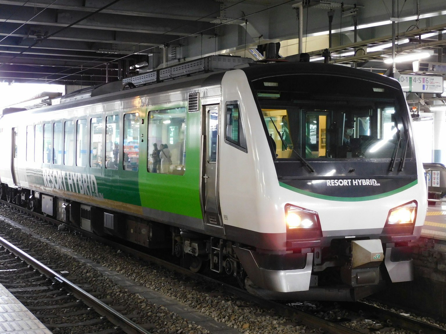 Kereta dengan desain hijau dan putih berhenti di stasiun
