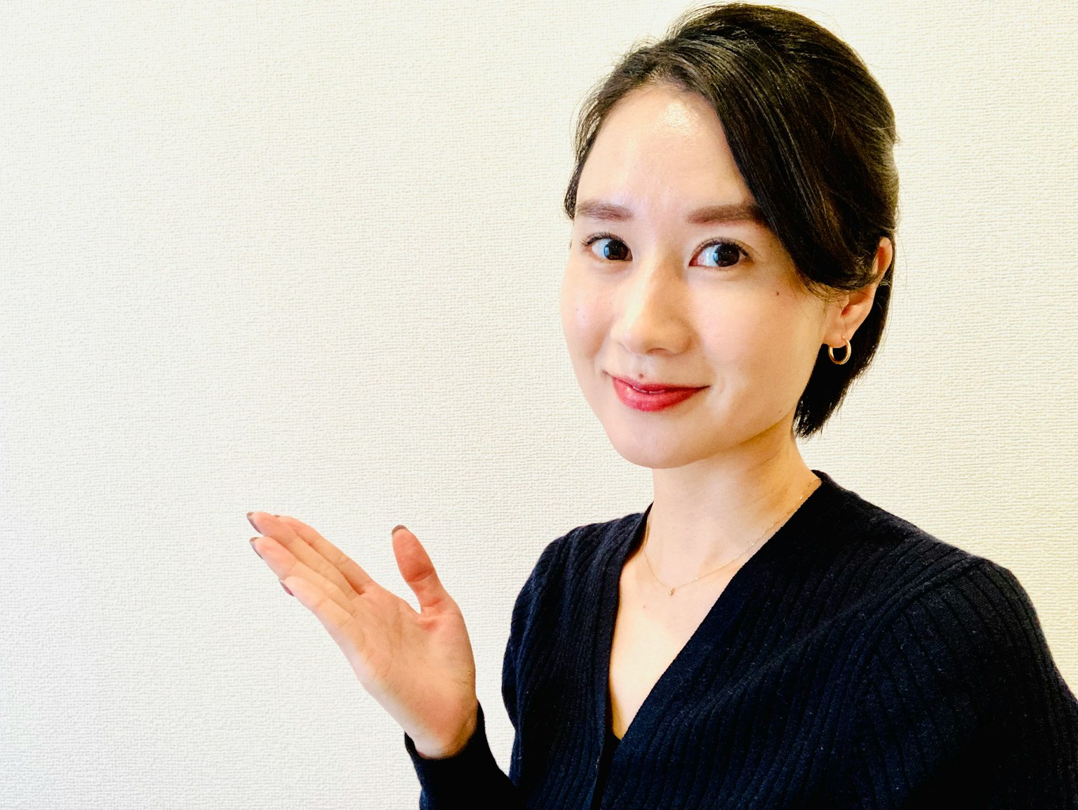 一位穿着黑色服装的女性微笑并用手做出手势