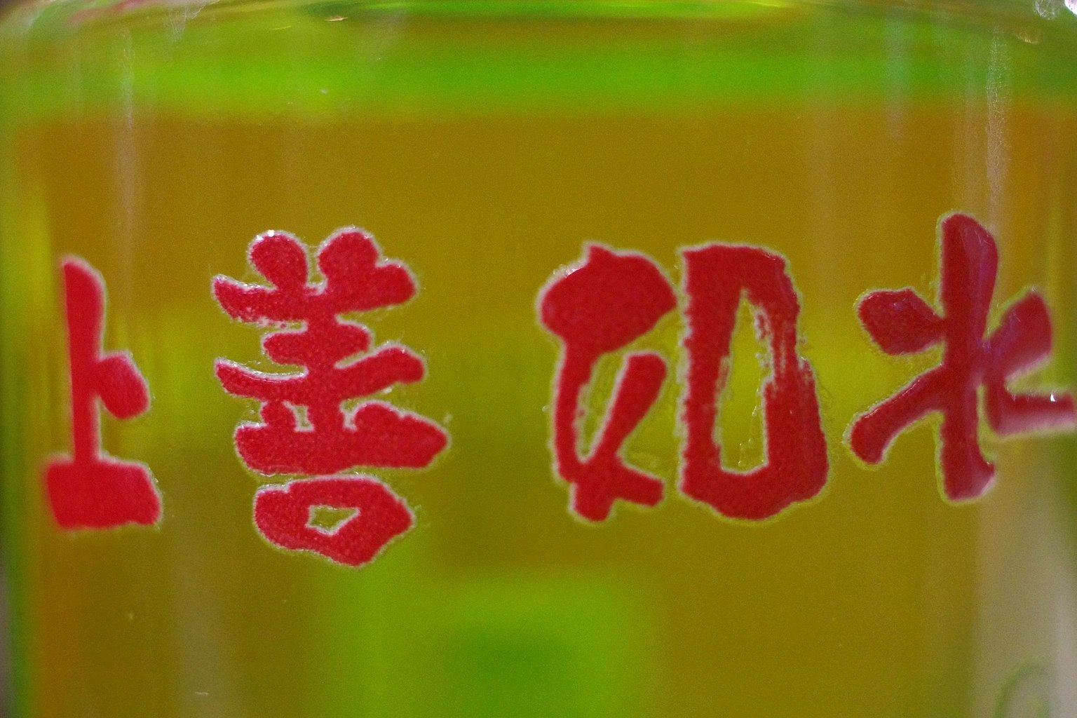 緑色の液体の瓶に赤い文字が書かれている