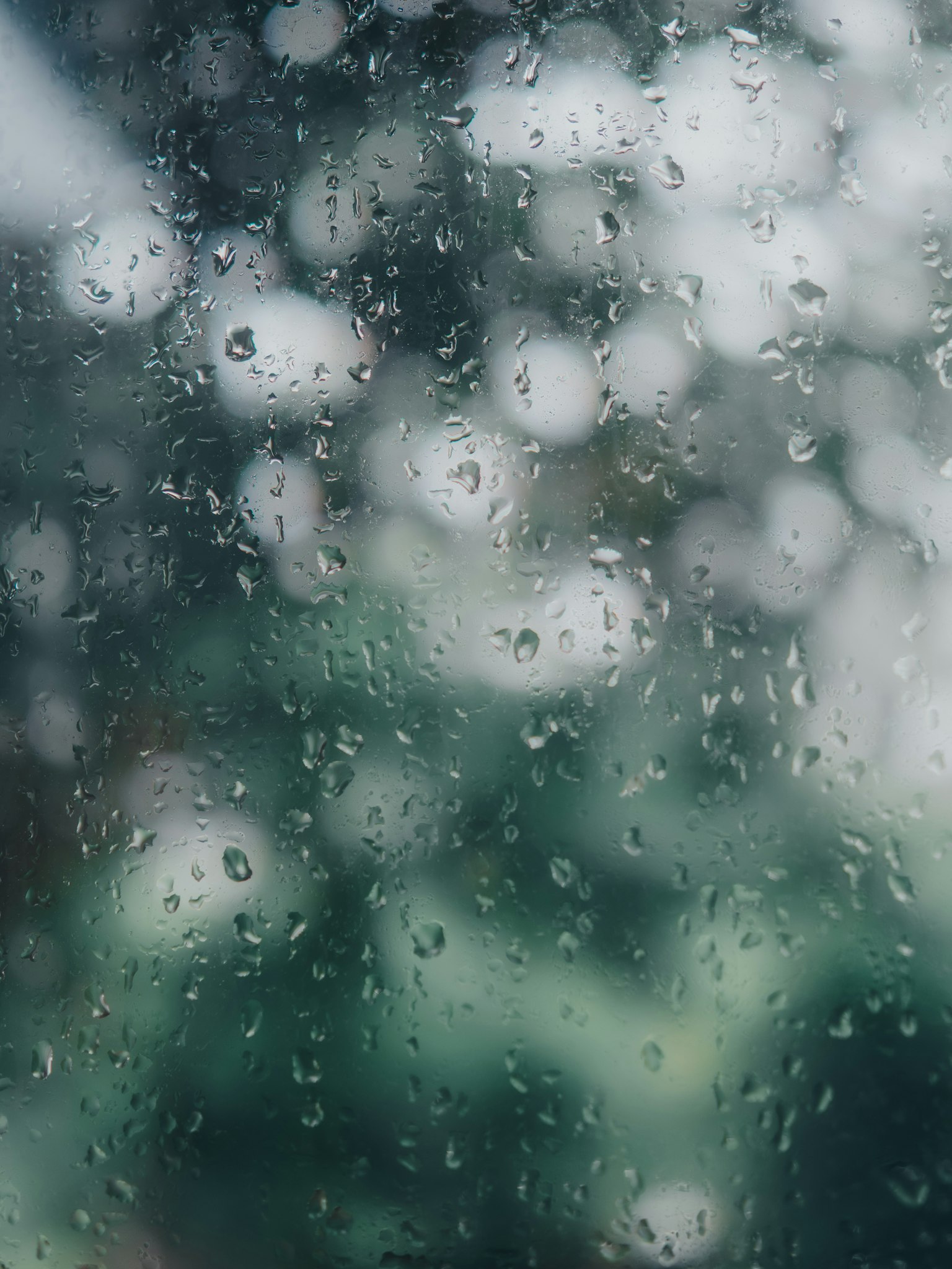 Blurred green landscape seen through a rain-speckled window