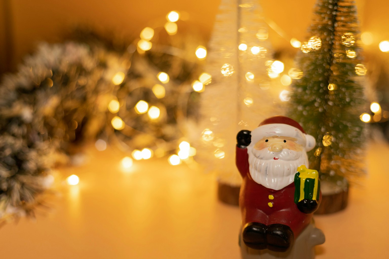 Tượng ông già Noel cầm quà với trang trí Giáng sinh ở nền