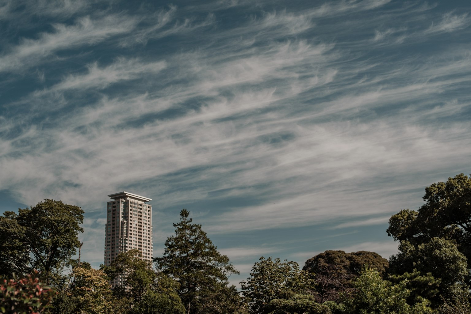 Städtische Skyline mit einem hohen Gebäude und verstreuten Wolken