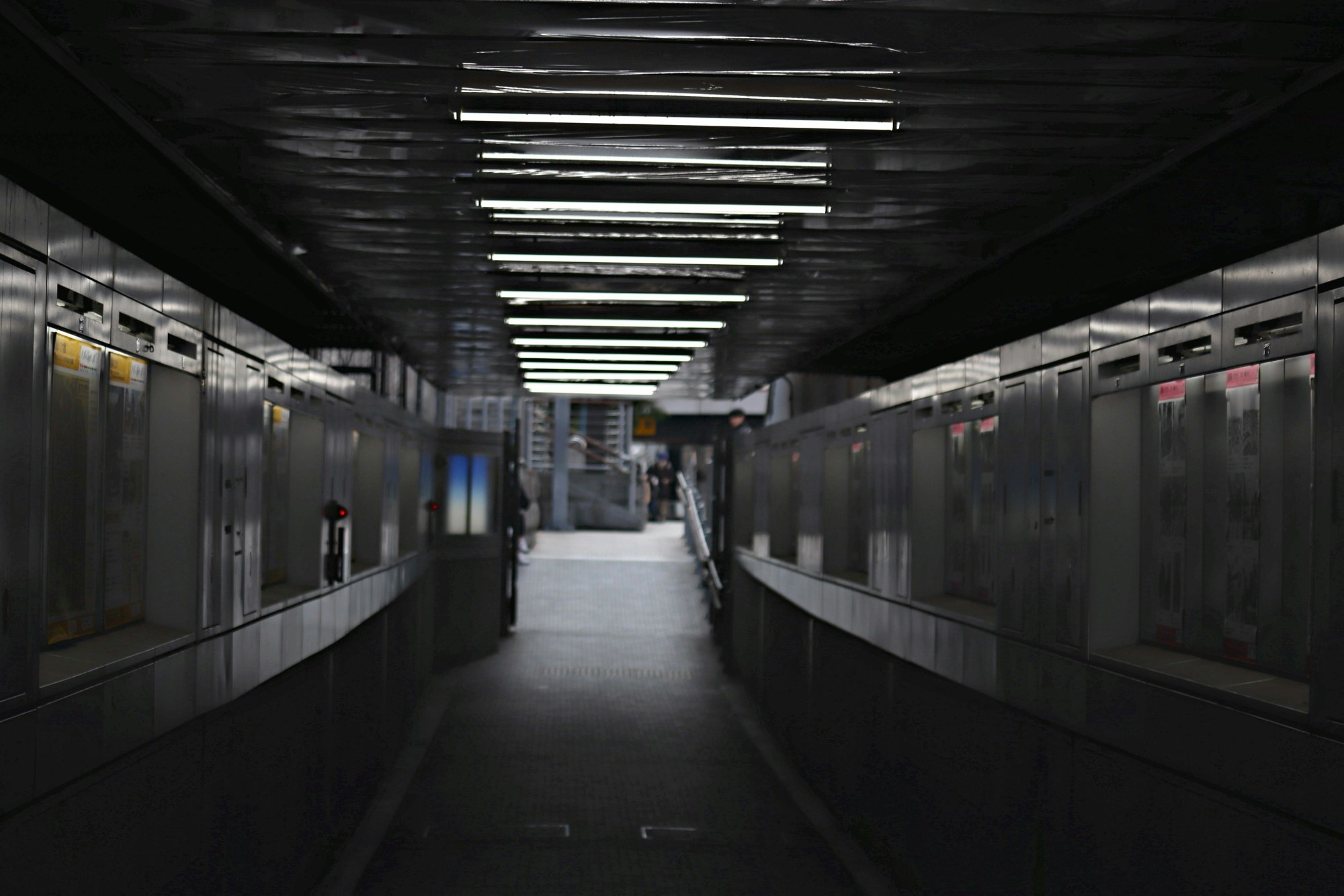 地下鉄の長い通路に並ぶ車両と蛍光灯の光