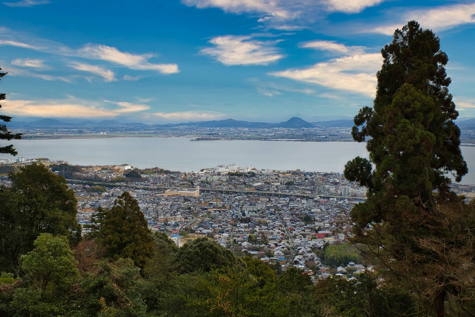 Scenic view of a city with a lake and mountains in the background