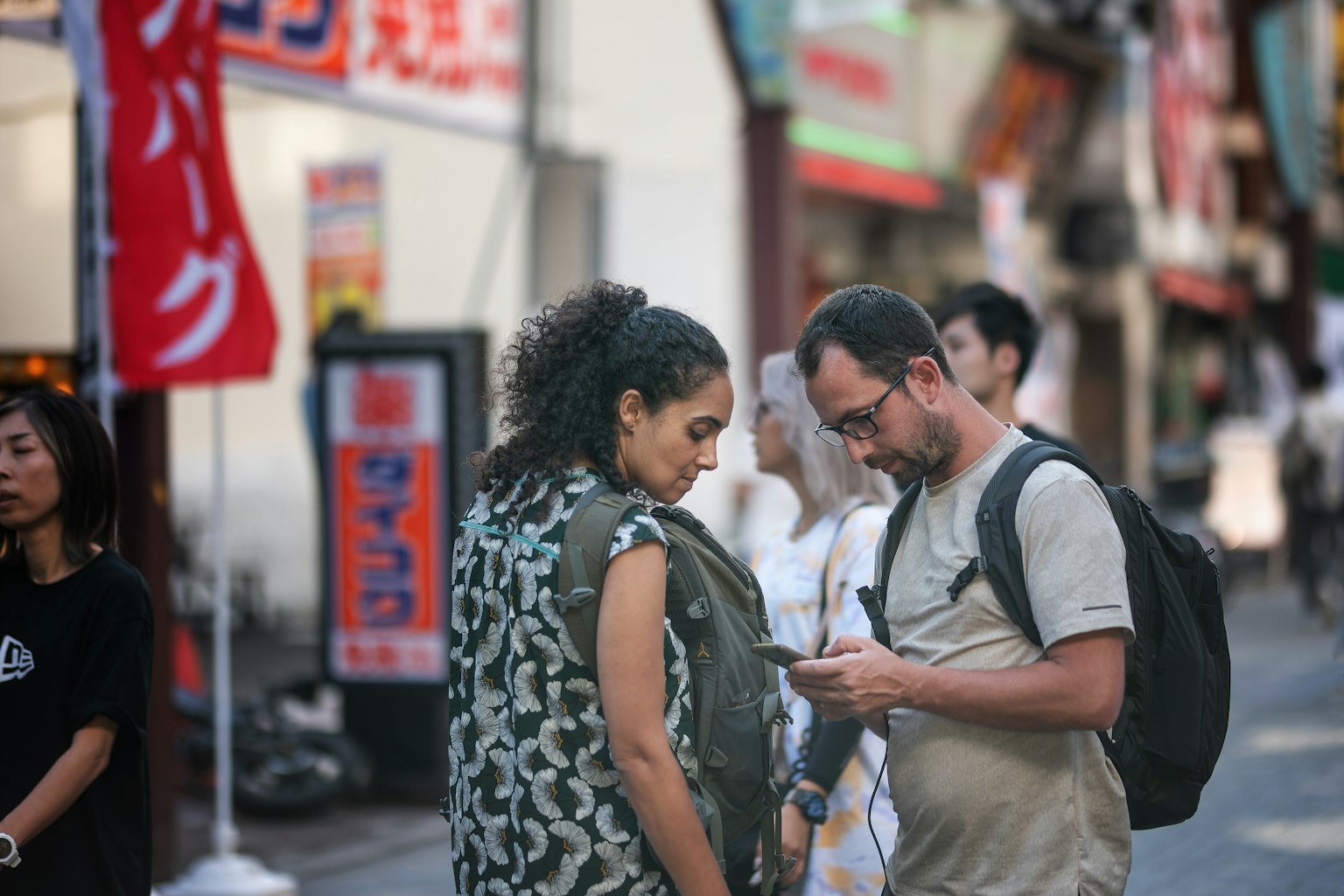 Two people checking a smartphone in a busy street with others around
