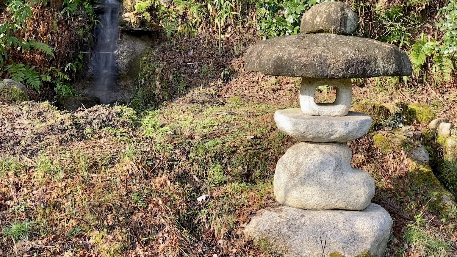 Lanterne en pierre dans un jardin avec une petite cascade