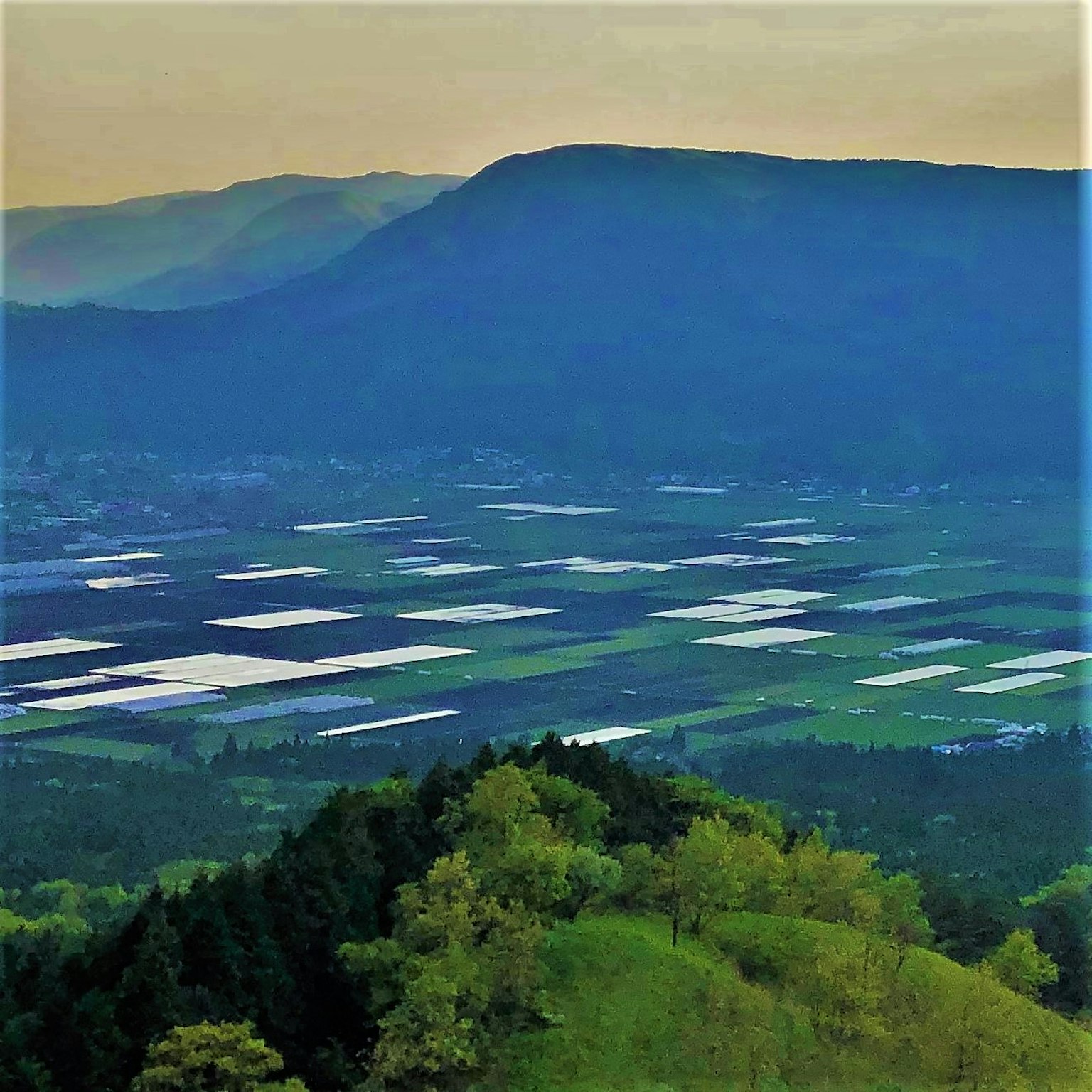 Hermoso paisaje de montañas y extensas tierras agrícolas Colinas verdes y invernaderos blancos visibles