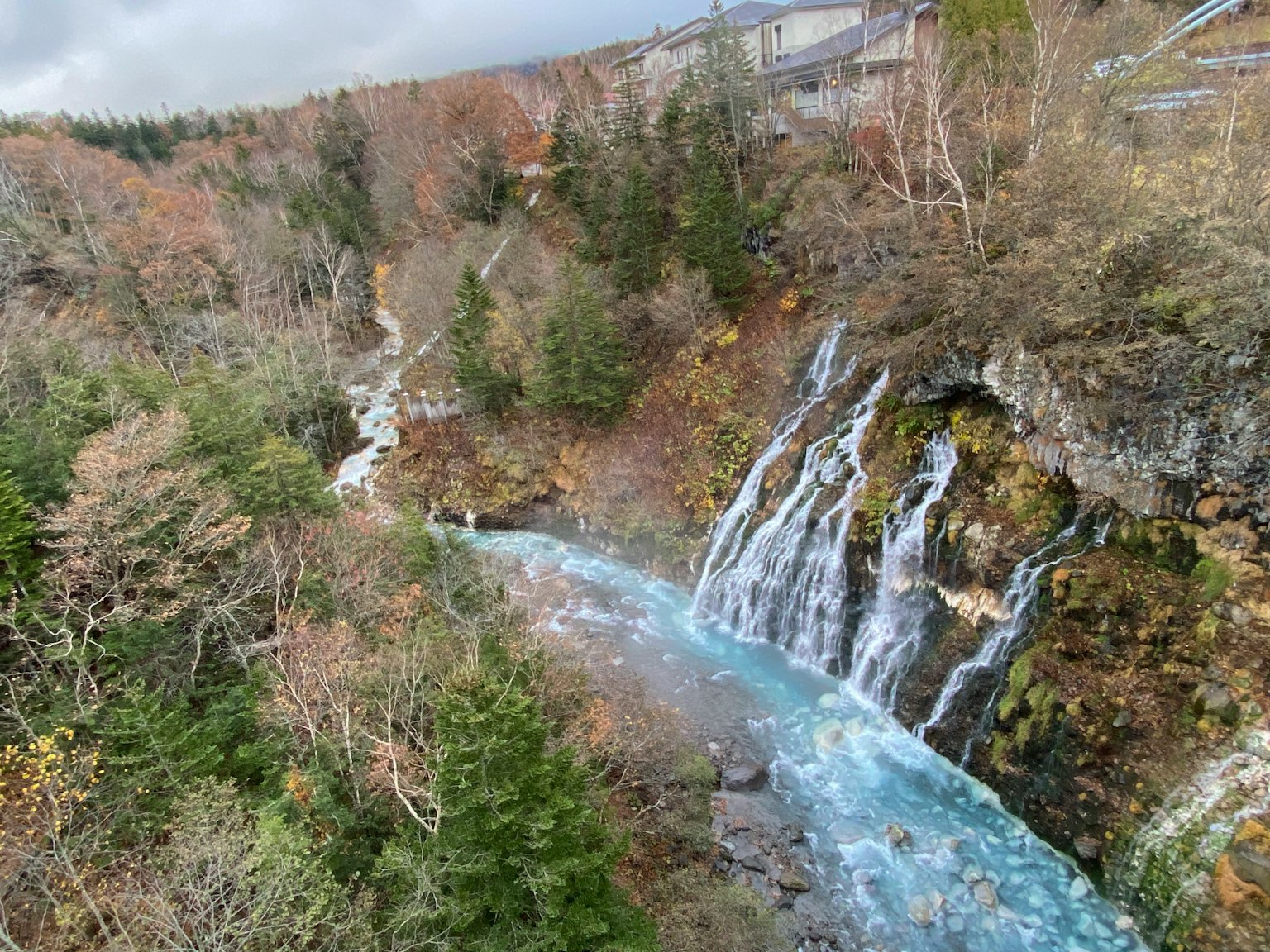 Vue pittoresque d'une cascade avec un ruisseau bleu entouré de feuillage d'automne