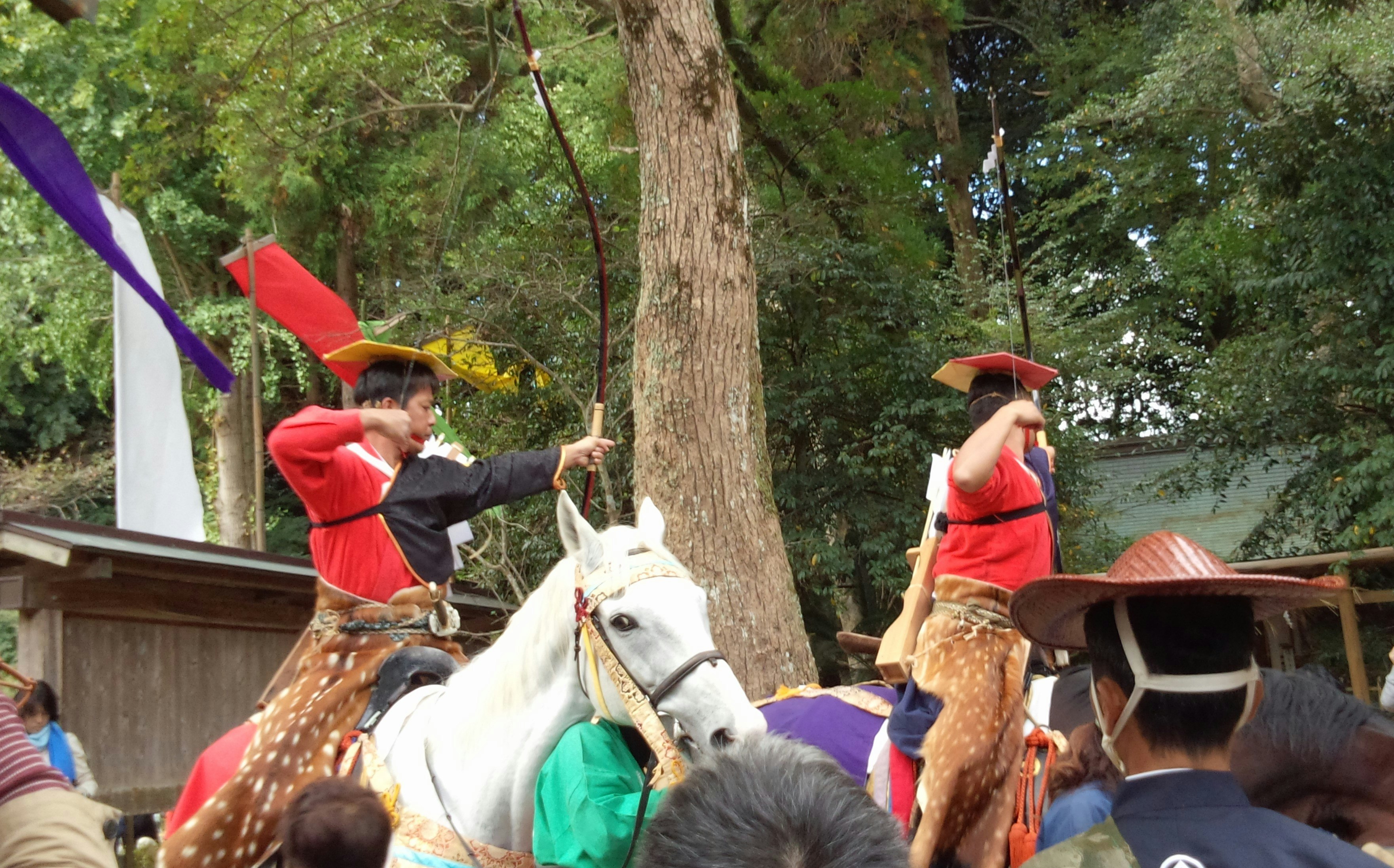 木陰の馬に乗る子どもたちと赤い衣装の参加者