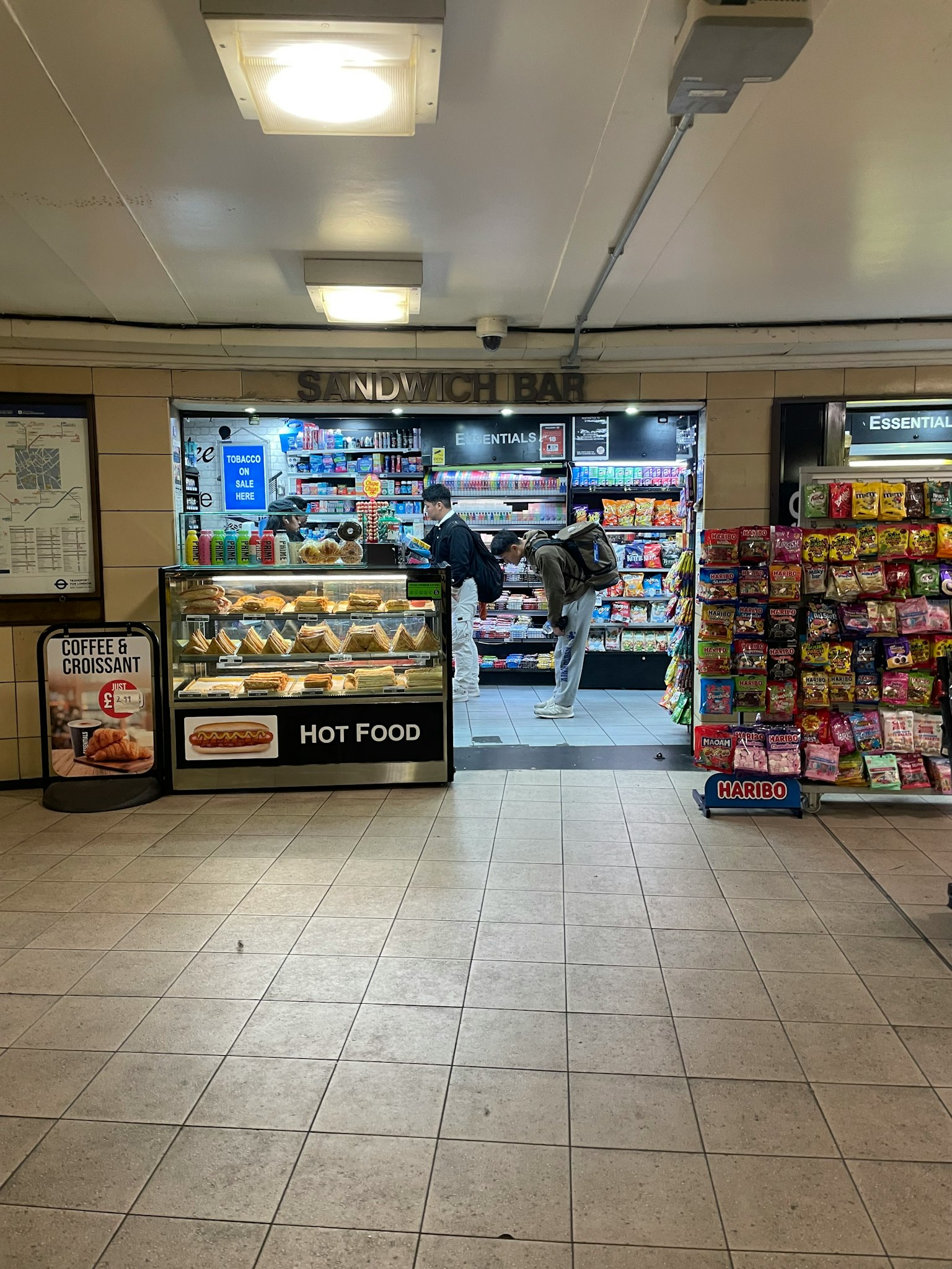 Personas seleccionando productos en un quiosco y café en una estación de metro