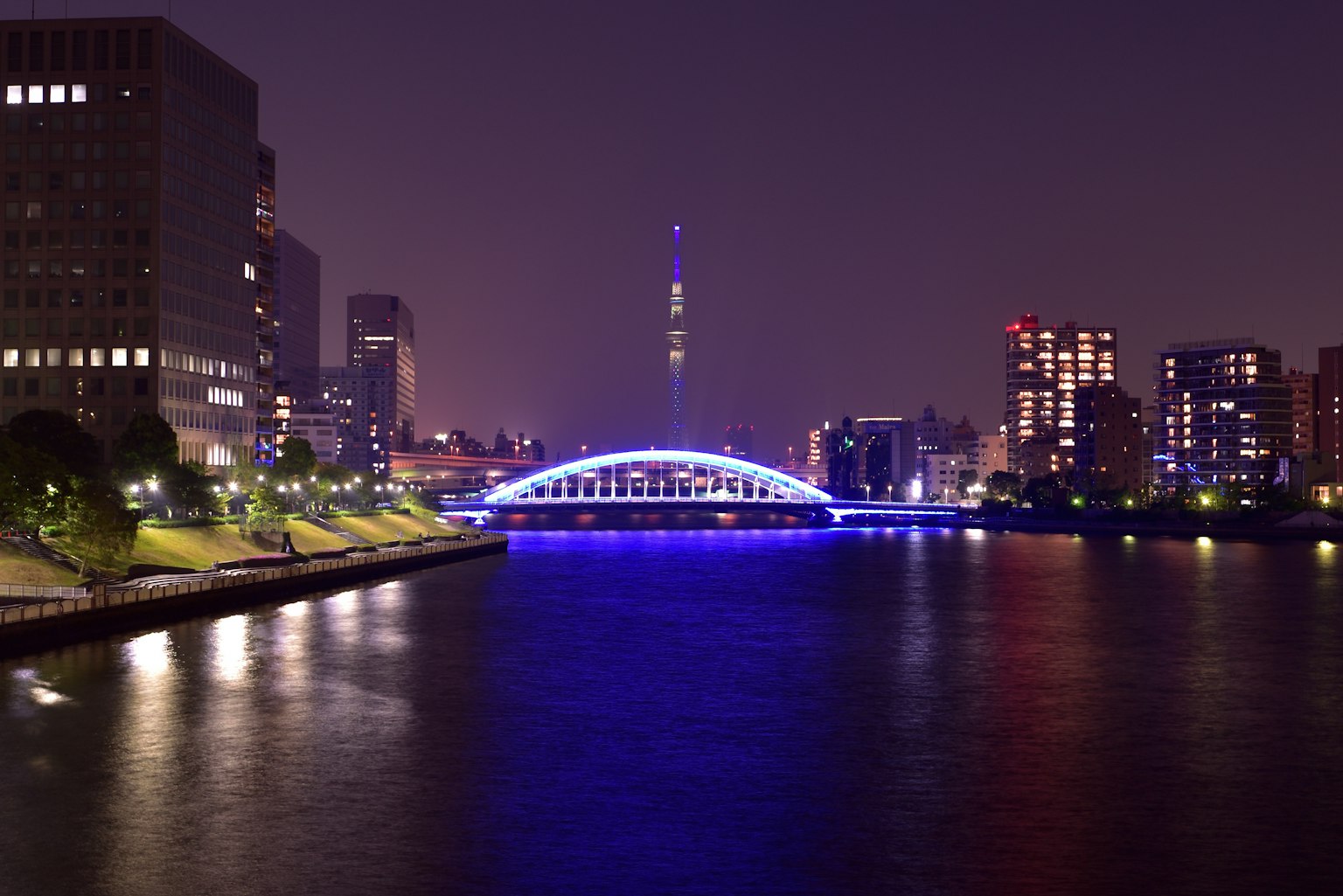 Tokyo Skytree bei Nacht beleuchtet mit einer blauen Brücke