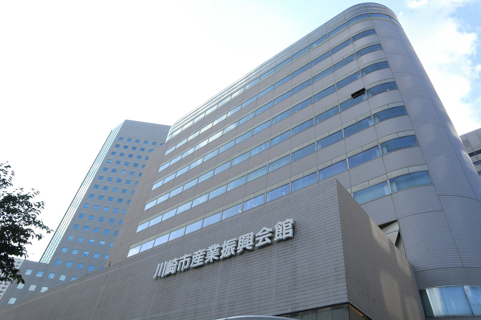Modern building exterior with glass and metal facade reflecting blue sky