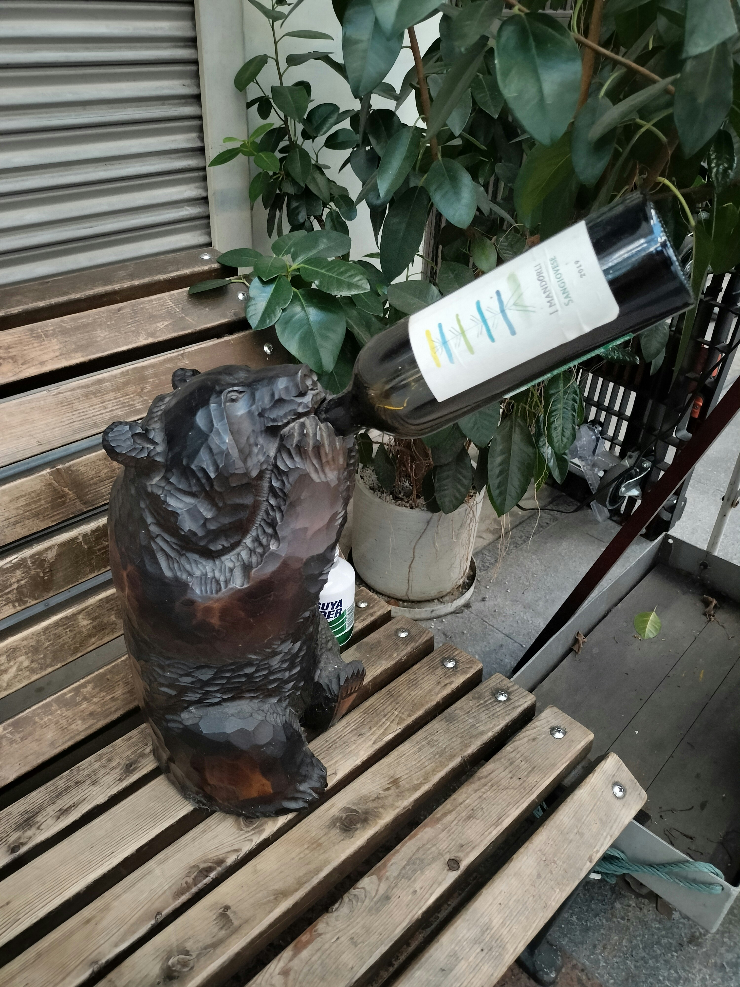 倉敷の木製ベンチに置かれた花と置物のある店先