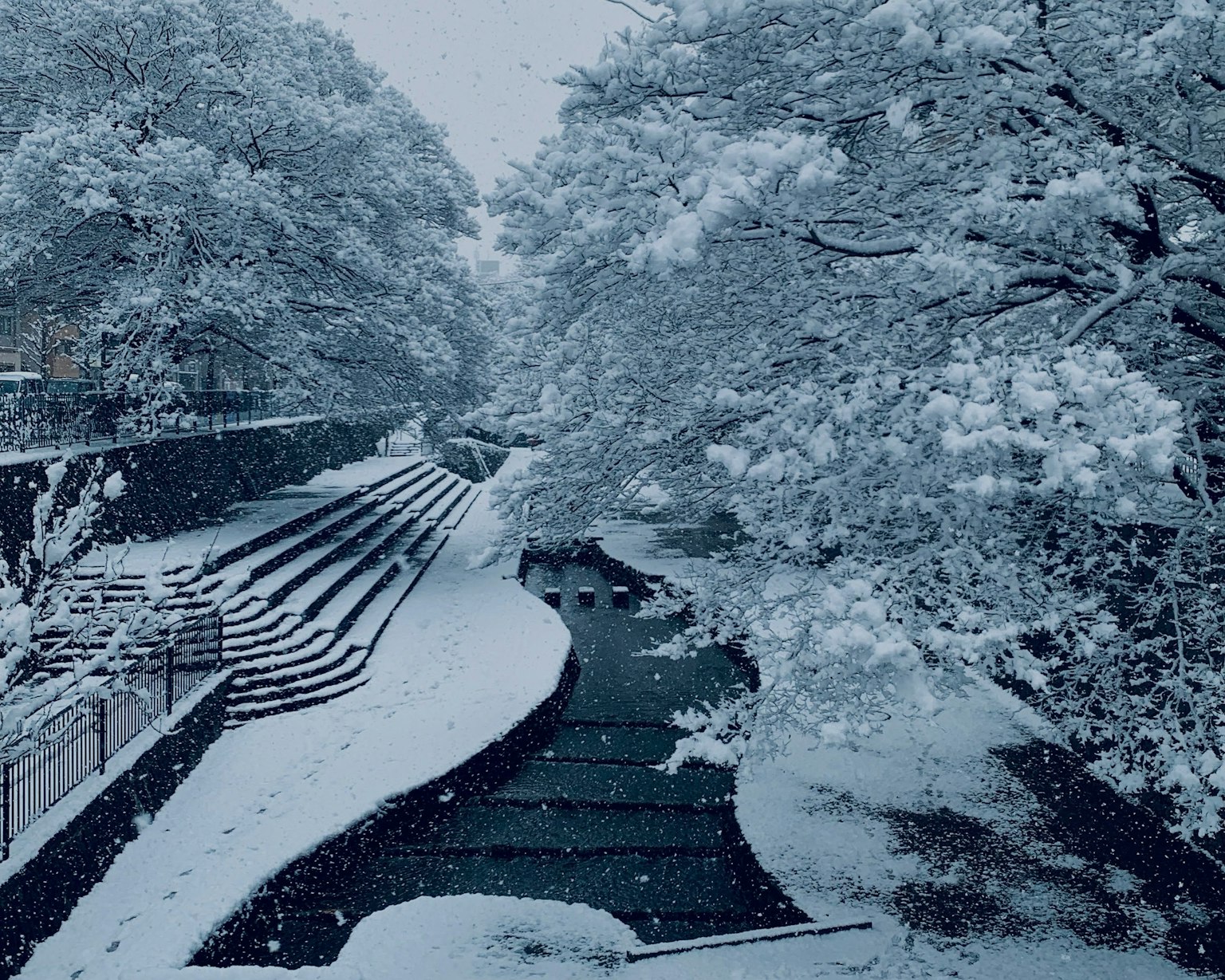 Schneebedeckter Fluss und Treppen in einer Winterlandschaft