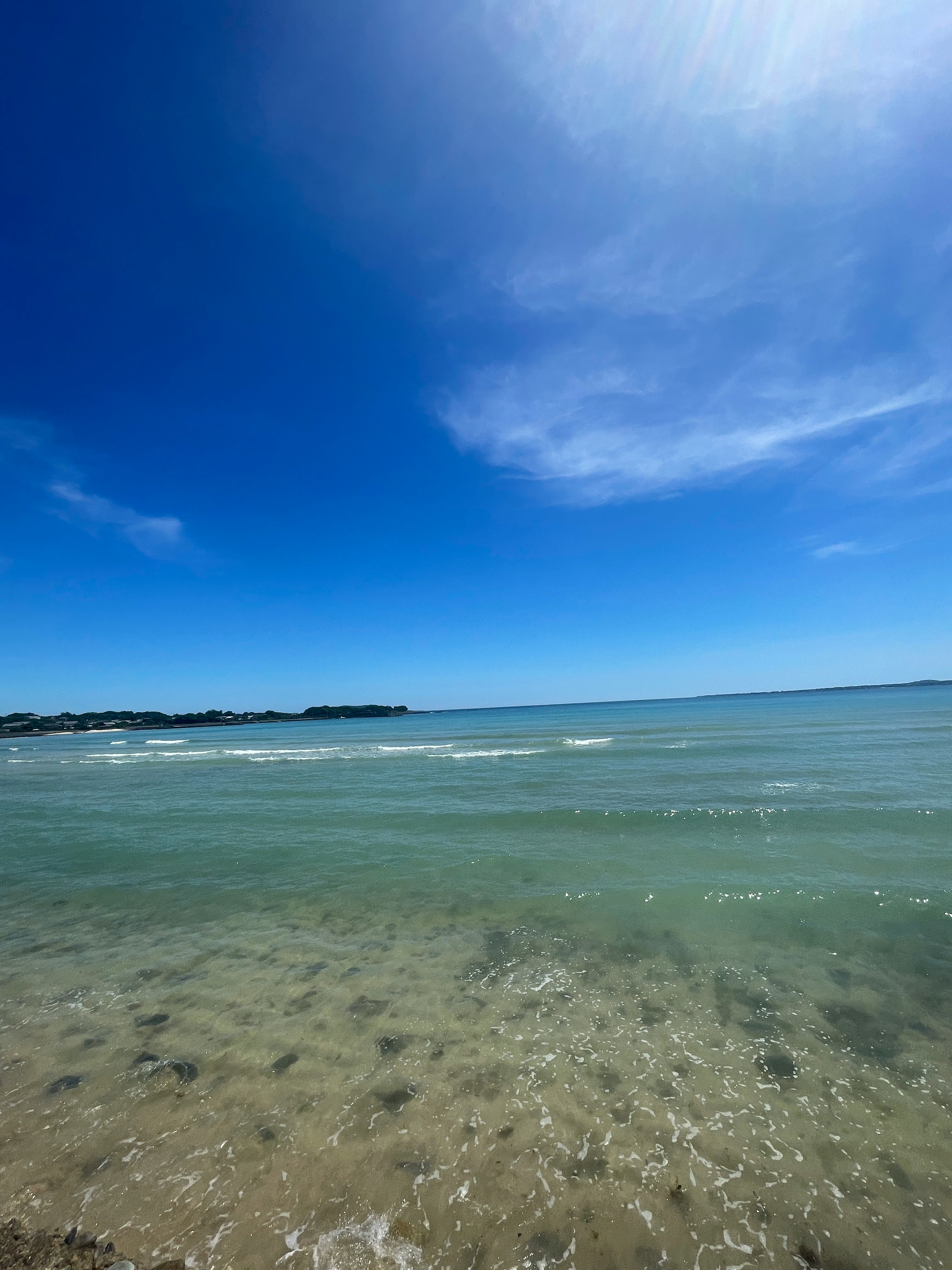 青いグラデーションの海辺の透明感ある波と空