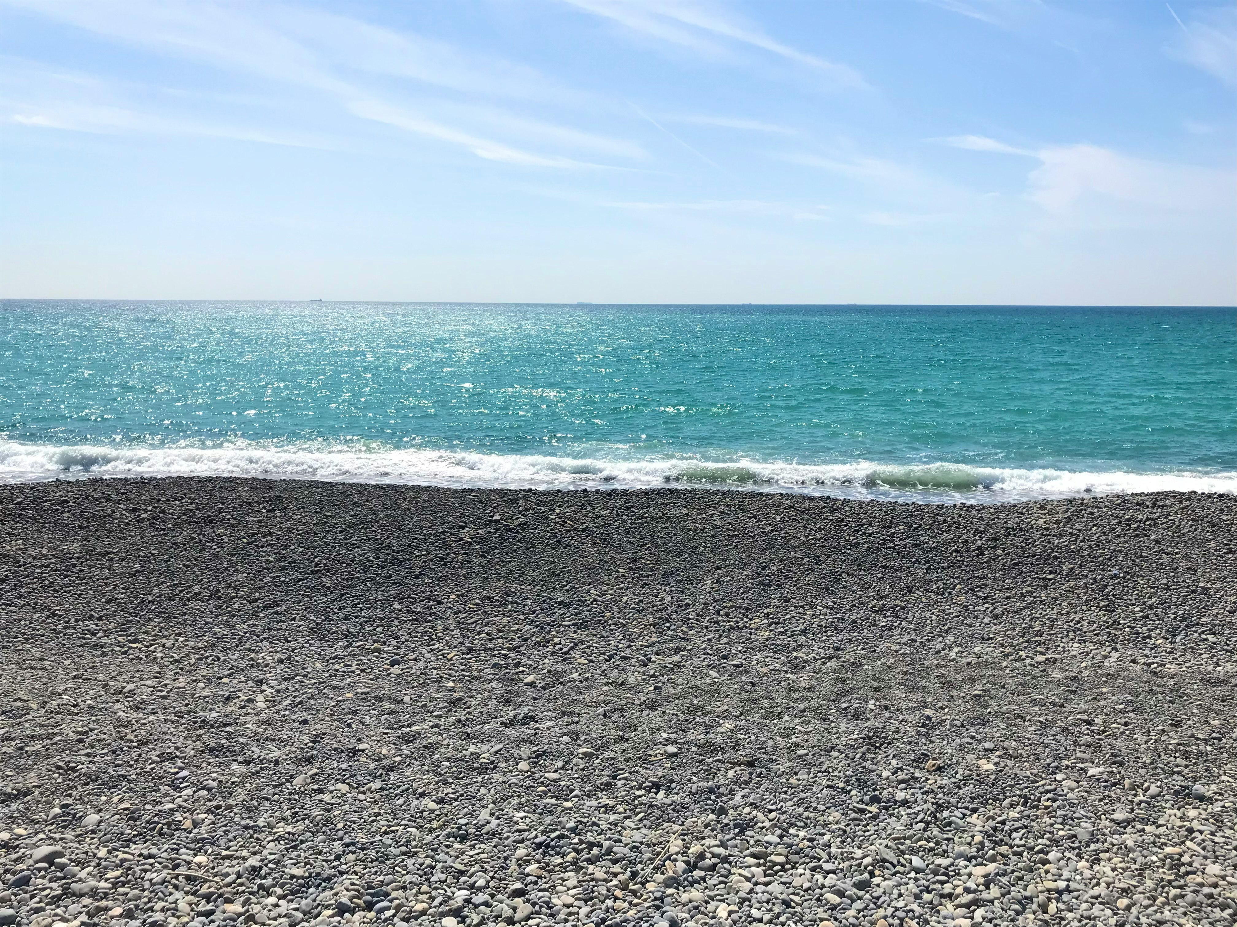波打ち際の黒い砂浜と青い海の水平線