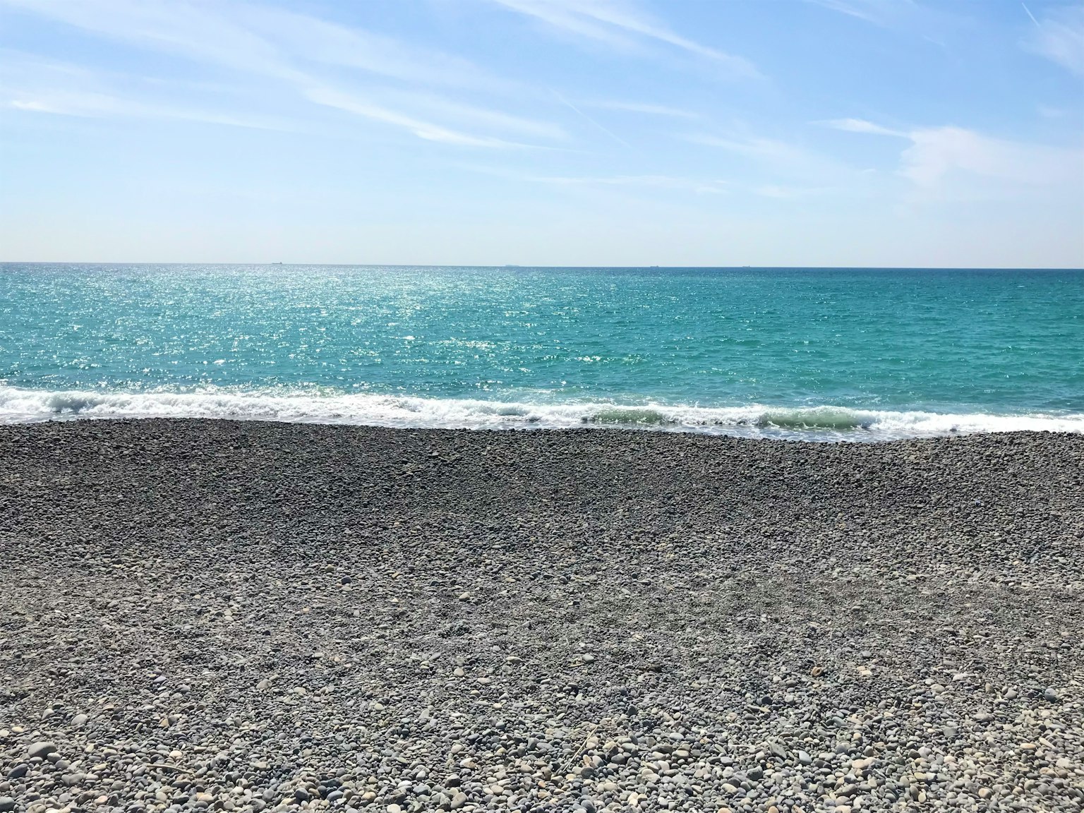一個岩石海灘，海水清澈，波浪溫和