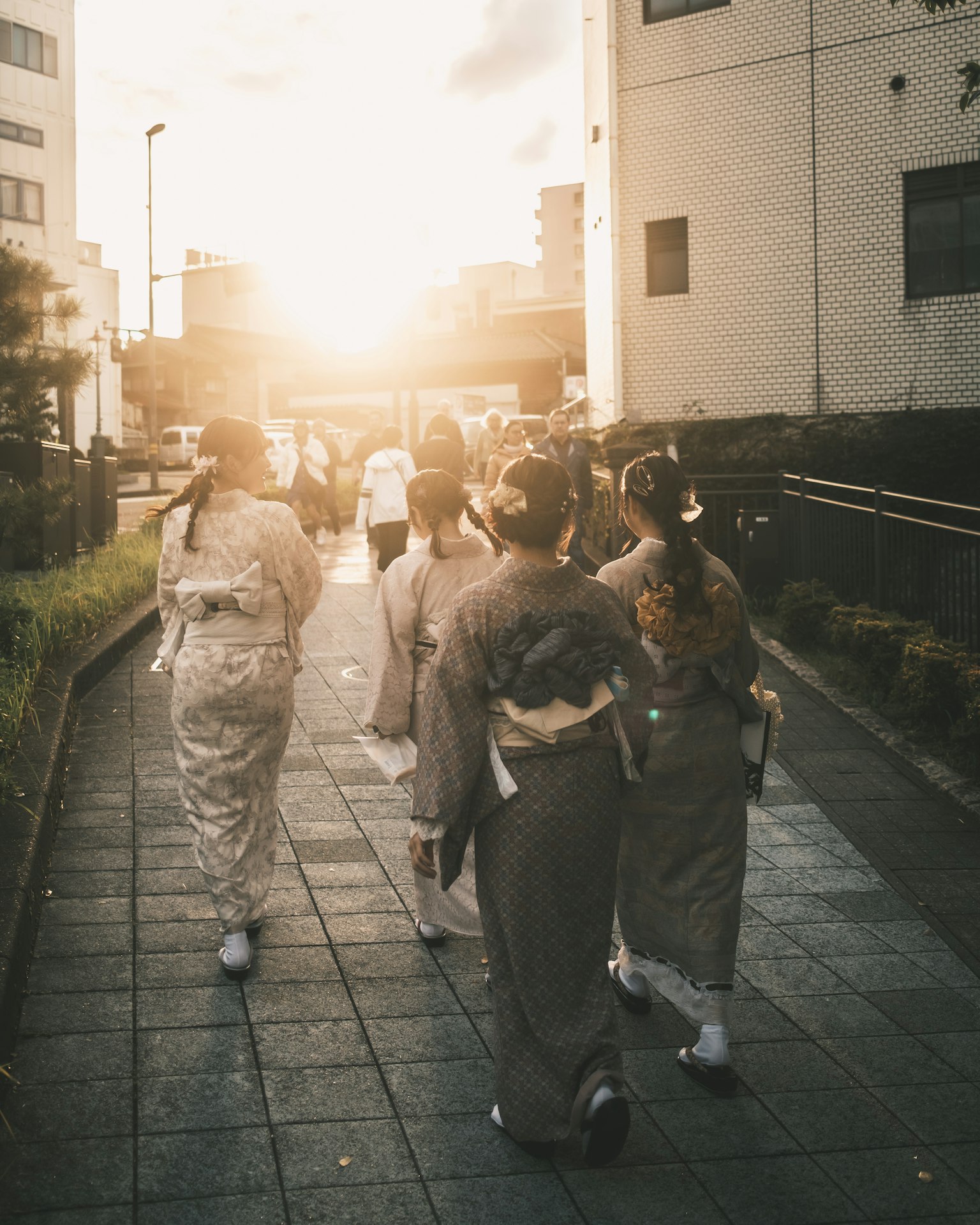 Frauen im Kimono gehen mit dem Sonnenuntergang im Hintergrund