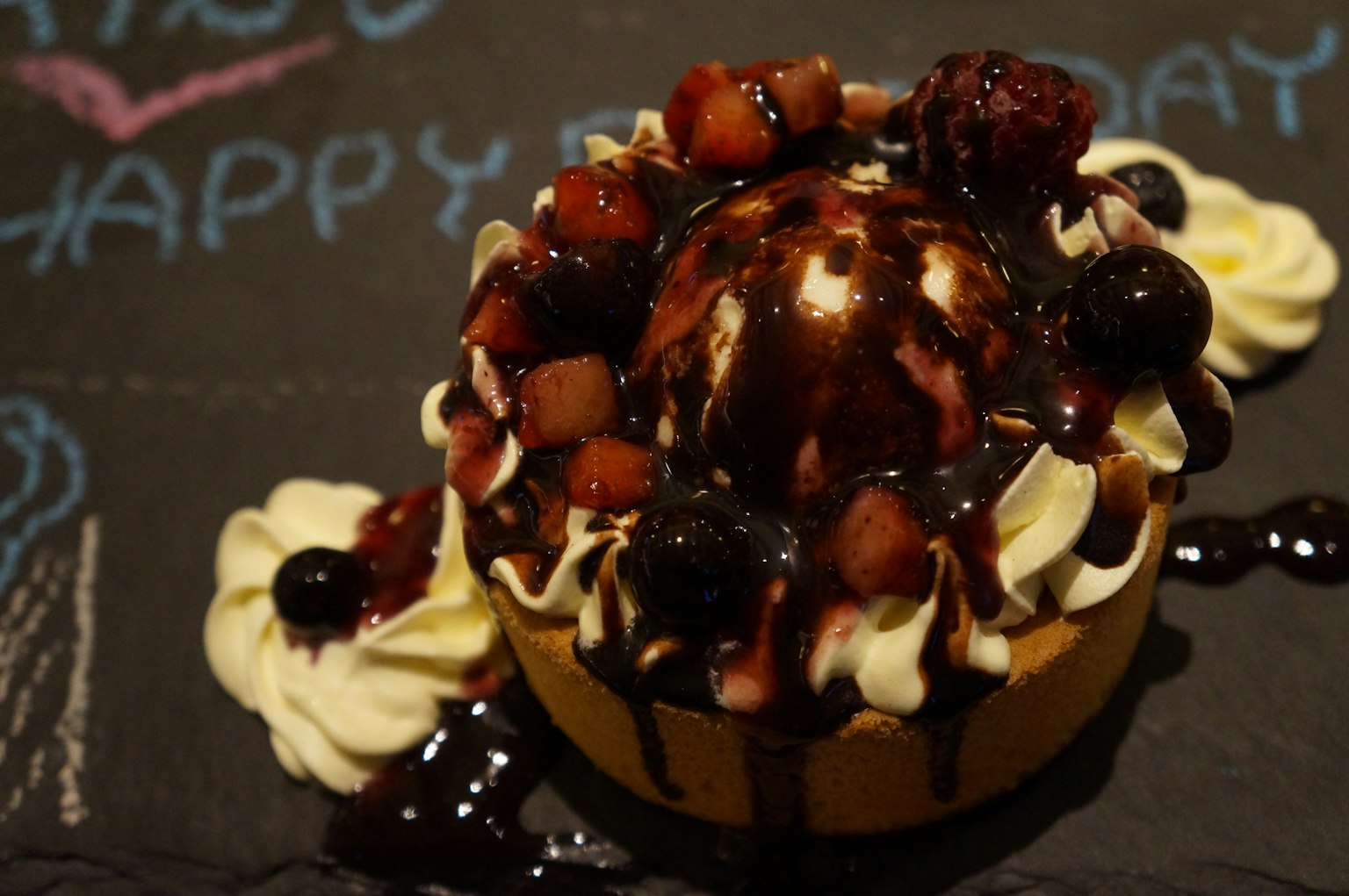 생일 케이크에 초콜릿 소스와 과일이 얹혀져 있음