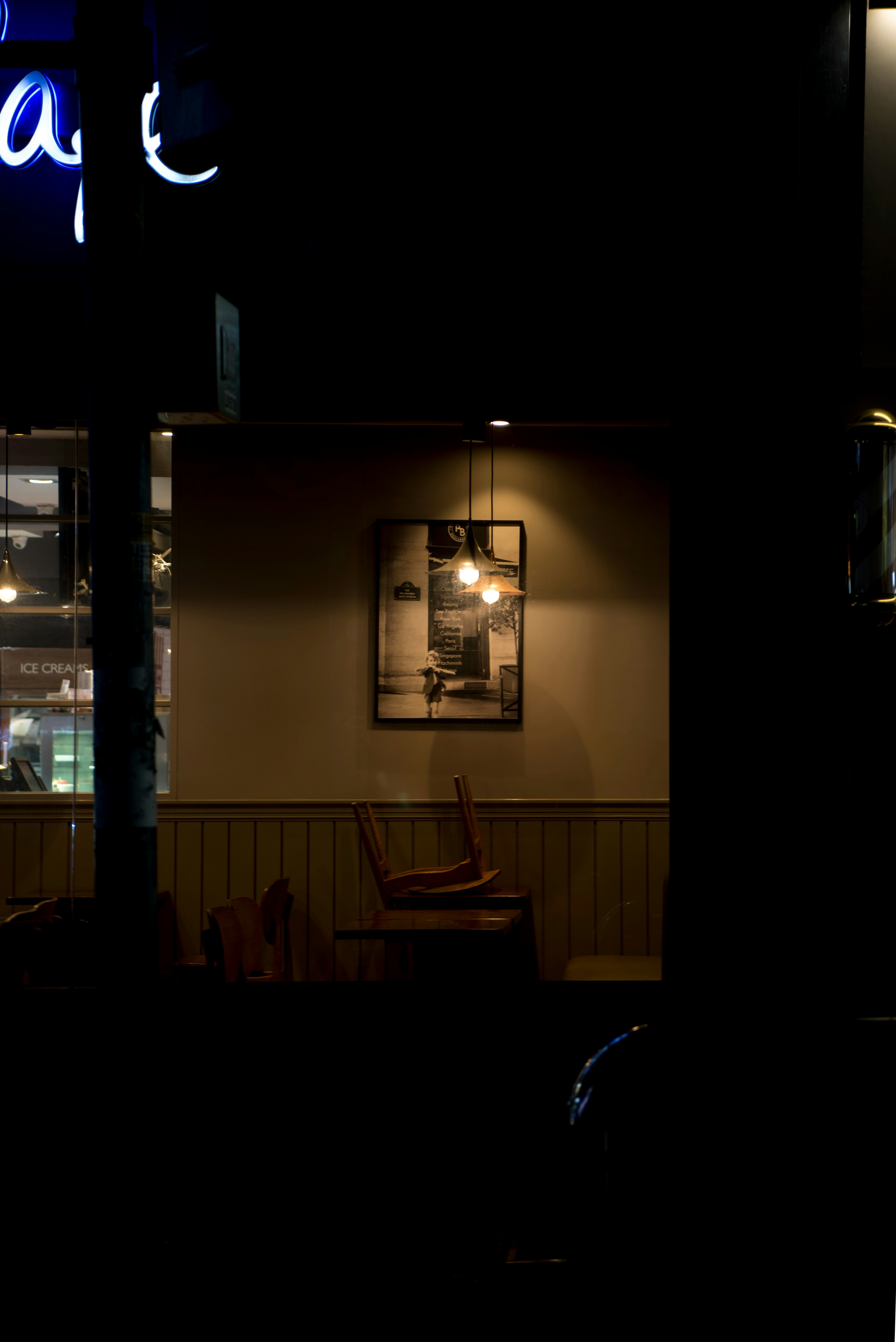 夜の店先に灯る看板とベンチのある路地の外観
