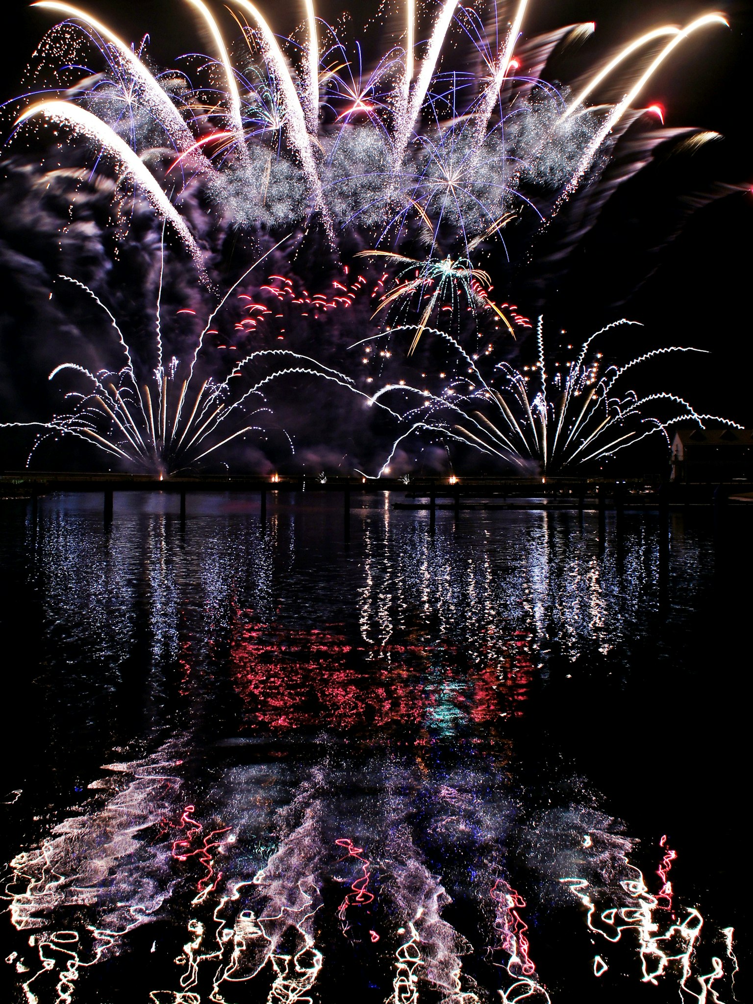 Vibrant fireworks display in the night sky with colorful reflections on the water