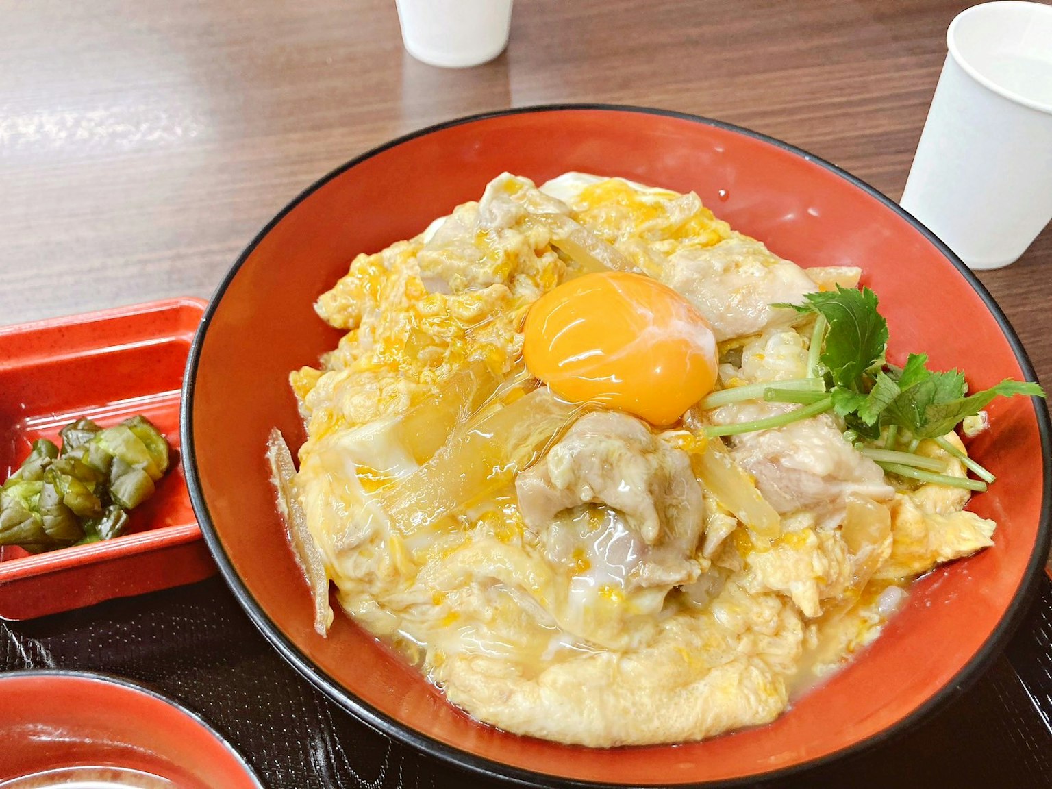 ชามโอยาโกะดงที่มีไก่และไข่เสิร์ฟในจานสีแดงข้างๆจานเล็ก