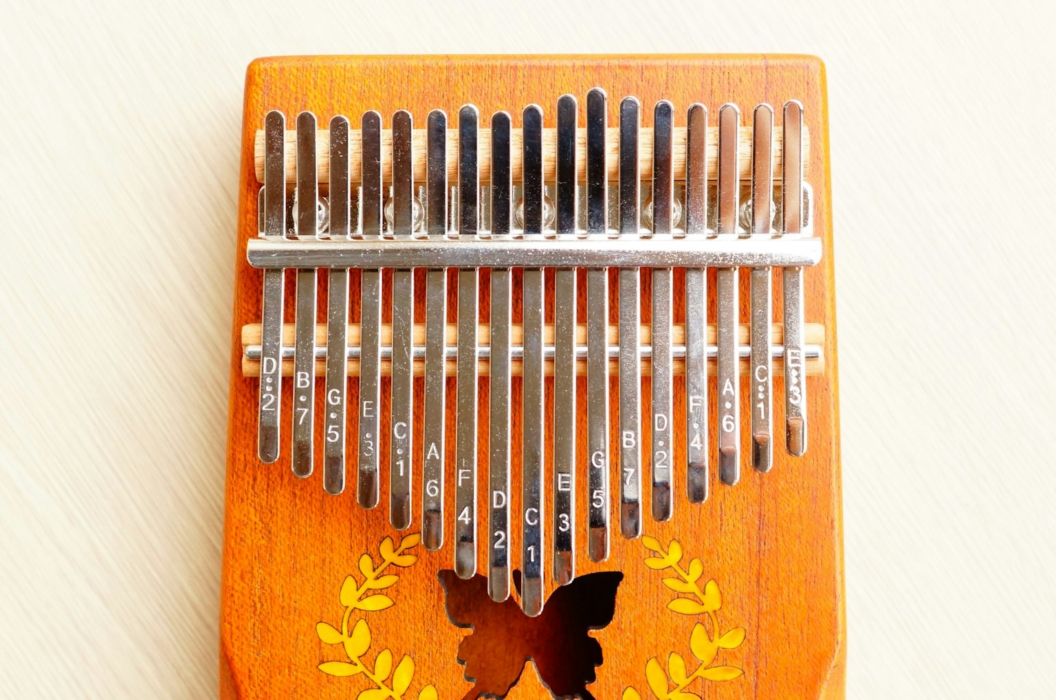 Vista superior de un kalimba de madera con lengüetas metálicas e ilustración de mariposa