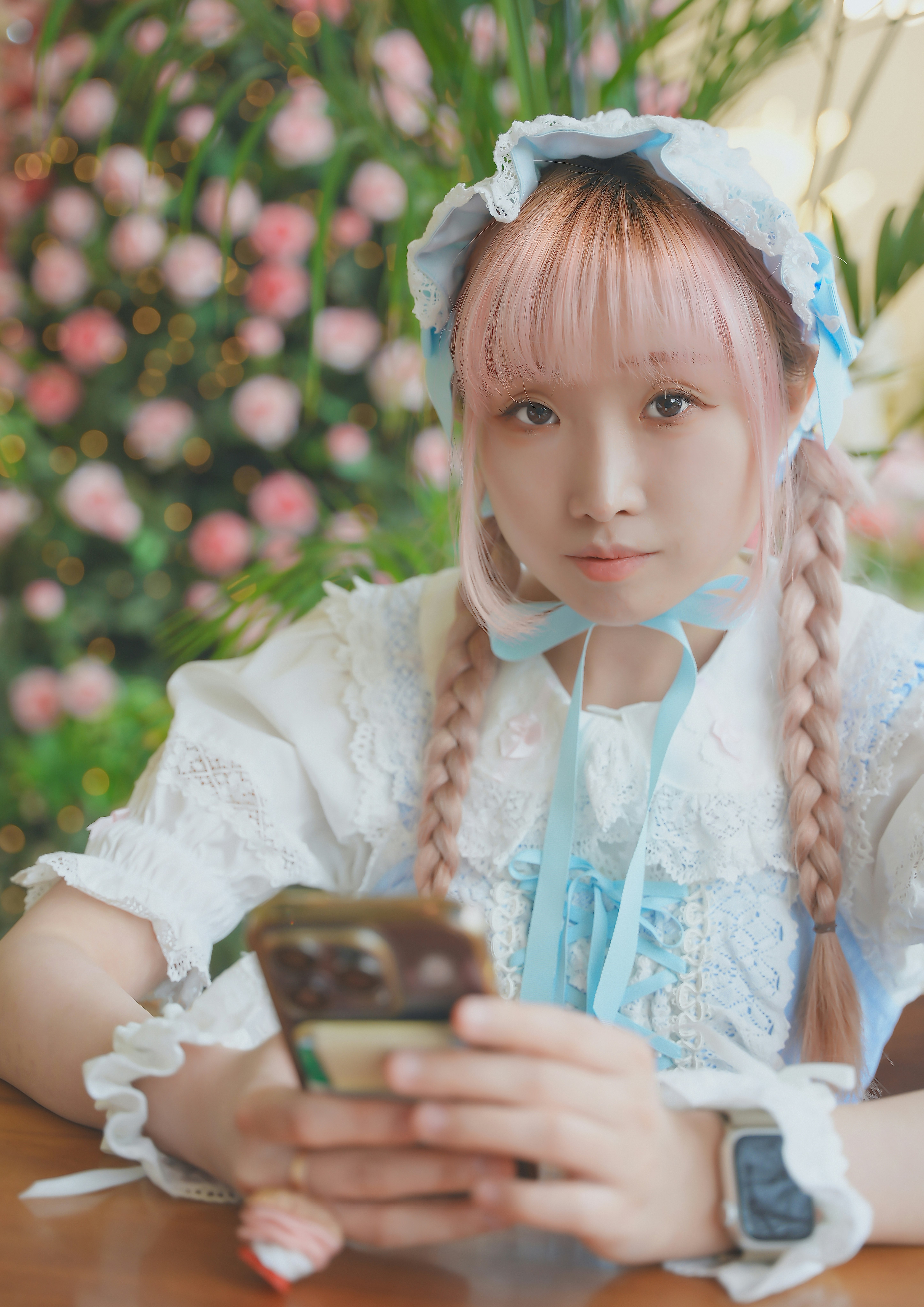 Una ragazza con un nastro blu circondata da fiori che tiene uno smartphone